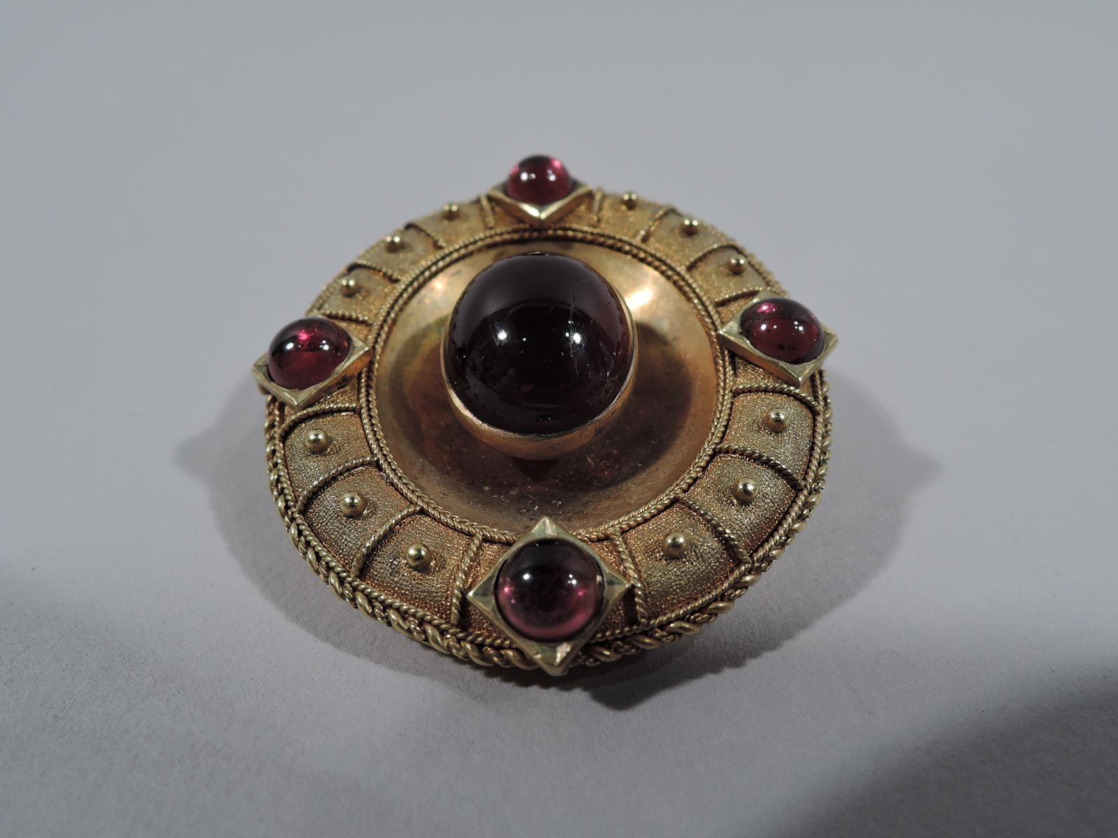 Etruscan Revival 18k gold and garnet brooch. Oval with large cabochon-cut garnet mounted to concave center. Four smaller cabochon-cut garnets mounted to shoulder, which is decorated with beaded rectilinear frames and rope rim. England, ca 1880.  