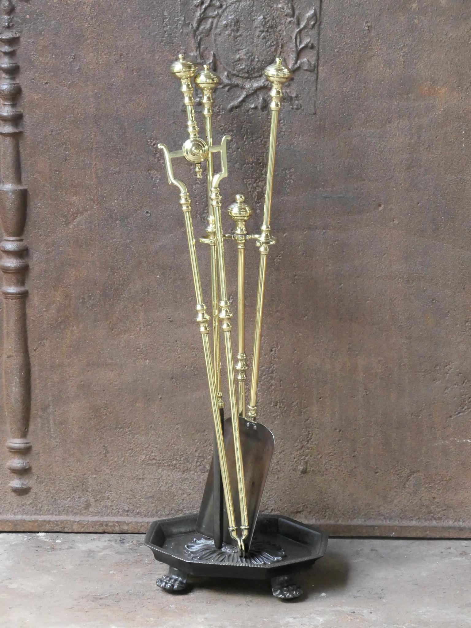 Set di attrezzi per caminetto del XIX secolo in stile vittoriano inglese. Gli strumenti sono realizzati in ottone lucido e ferro battuto, mentre il supporto è in ghisa e ottone lucido. Il set di attrezzi è composto da pinze, pala, attizzatoio e