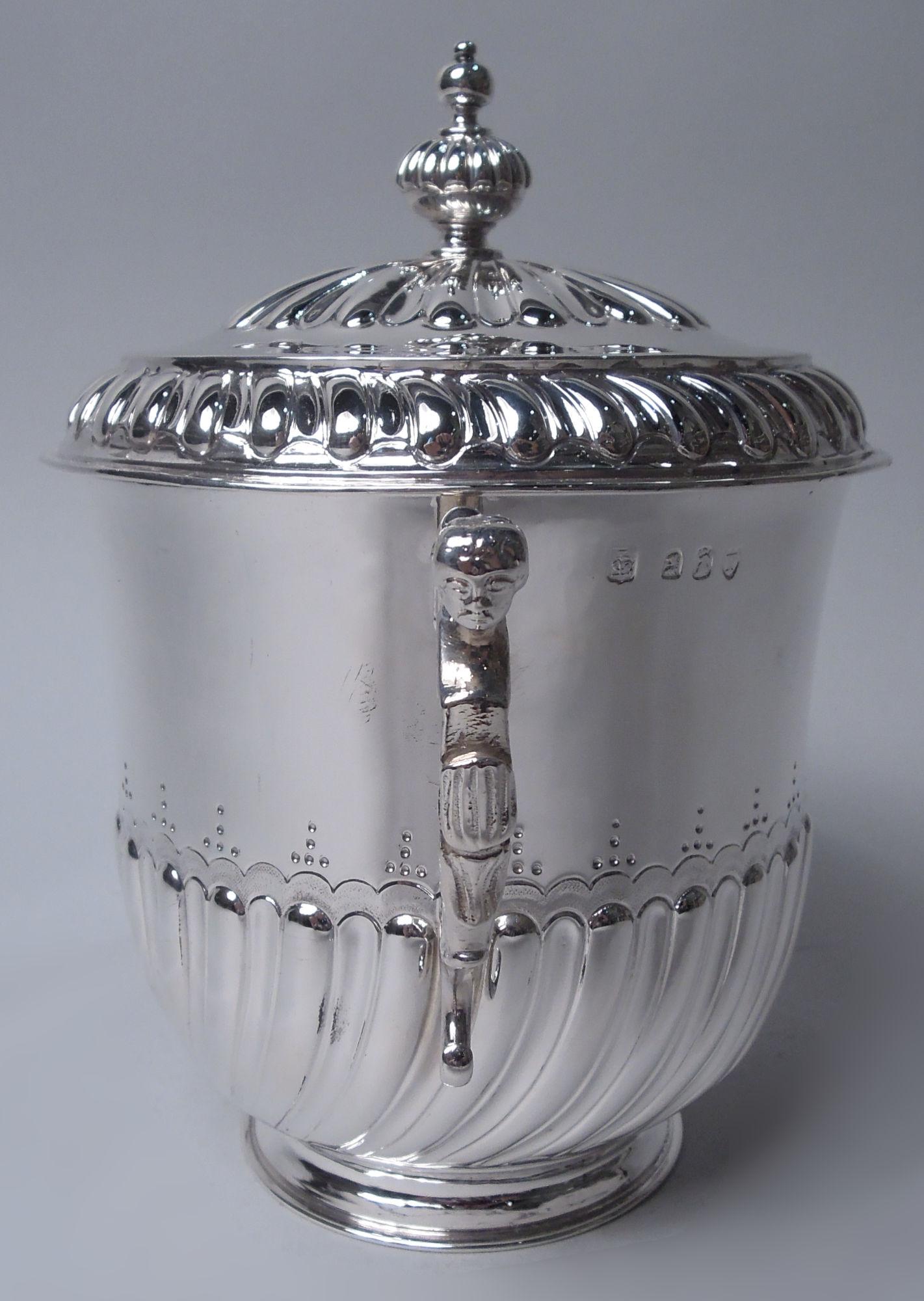 Urna coperta di epoca vittoriana georgiana. Prodotto da Lambert & Co. a Londra nel 1894. La ciotola ha una mezza scanalatura e una gadroonatura con bordo smerlato; manici a voluta fusi con teste femminili; piede rialzato. Coperchio a cupola con