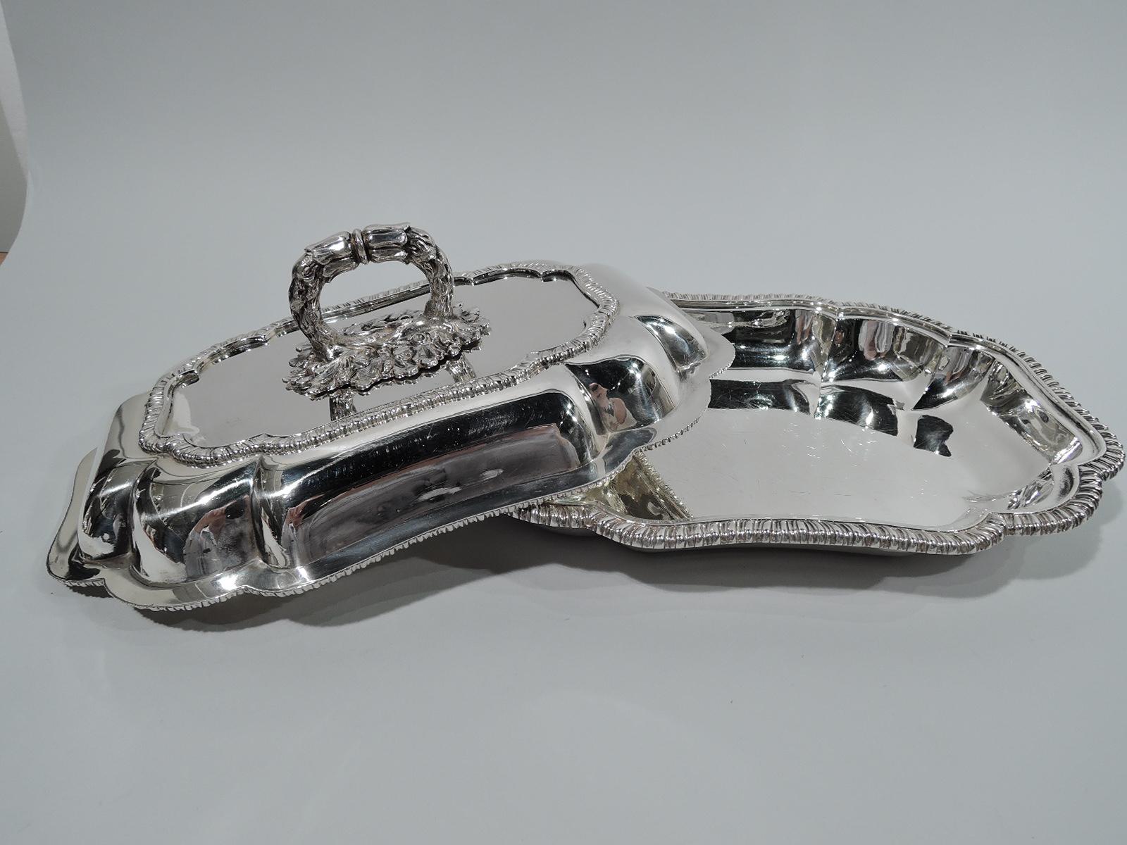 Victorian sterling silver covered serving bowl. Made by Benjamin Smith in London in 1841. Shaped rectangle with concave sides and ends, C-scroll corners, and gadrooned rim. Cover raised with gadrooned border. Cast leaf-mounted branch handle; twist