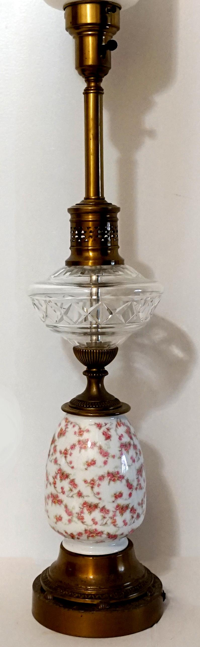 Handgemalte Rosen auf Porzellan und ein Lampenschirm aus Milchglas bilden den Mittelpunkt dieser romantischsten aller englischen Lampen, die auf einem hohen runden Messingfuß mit schöner Patina ruht. Die Lampe steht auf einer Messingstange über