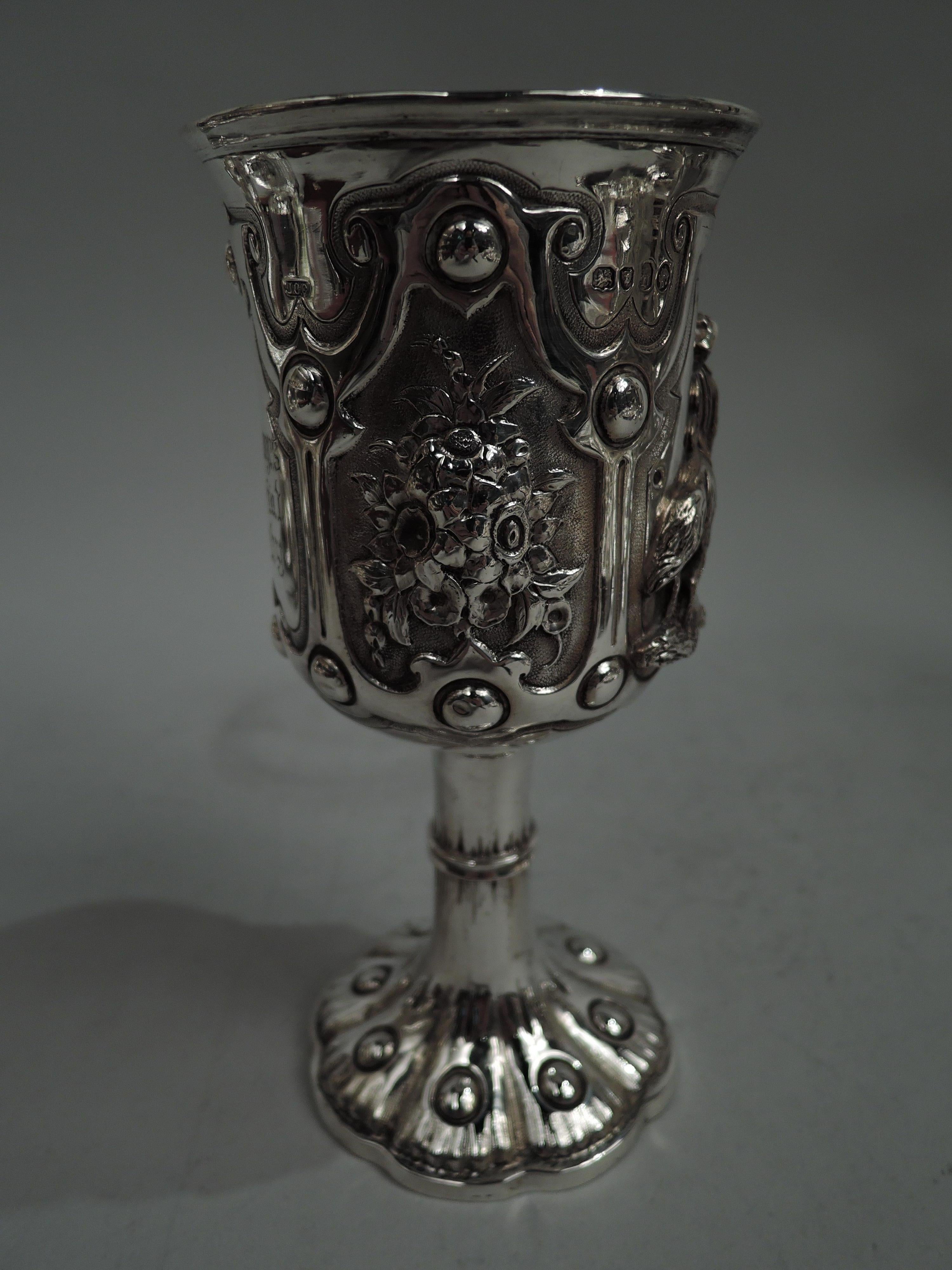 Victorian Gothic sterling silver goblet. Made by James Charles Edington in London in 1857. Tall and flared bowl with gilt interior; girdled cylindrical stem on raised foot with studded lobes and scalloped rim. Bowl has four studded and stippled