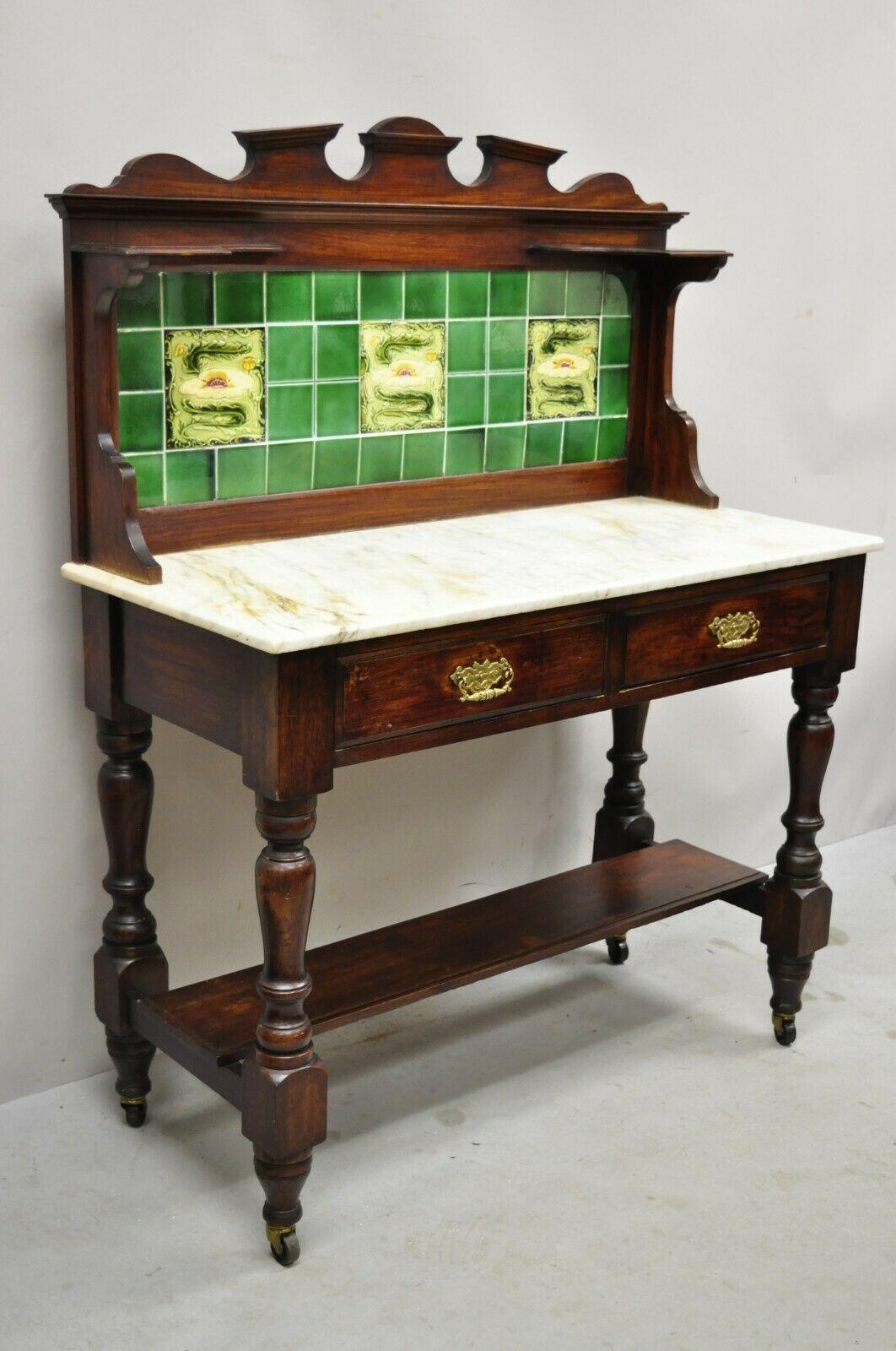 Antique English Victorian green ceramic tile backsplash marble top washstand commode. Item features a green porcelain ceramic title back splash , two small upper shelves, white marble top, lower shelf turned carved legs, 2 dovetailed drawers, solid
