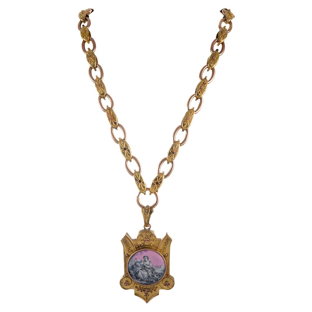 Relicario de oro amarillo y rosa de 15 quilates, el anverso decorado con un retrato en miniatura en rosa, gris y blanco de una dama cuidando de sus mascotas, y enmarcado por un ornamentado y delicado despliegue de granulación. Esta pieza ofrece una