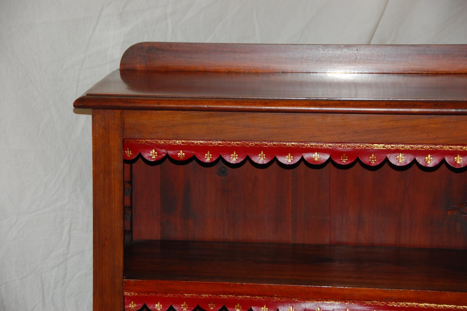 English Victorian period mahogany bookcase with three adjustable shelves. The edges are enhanced by red tooled leather edgings. These are removable if desired. The leather is replaced and hand tooled. It was copied from the original leather edgings