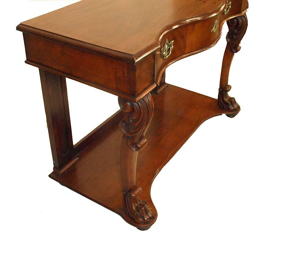 English Victorian mahogany serpentine console table , the molded edge top with serpentine shape, the single drawer following that shape having vertical crotch mahogany veneer and ornate brass pulls and escutcheon; acanthus carved cabriole front legs