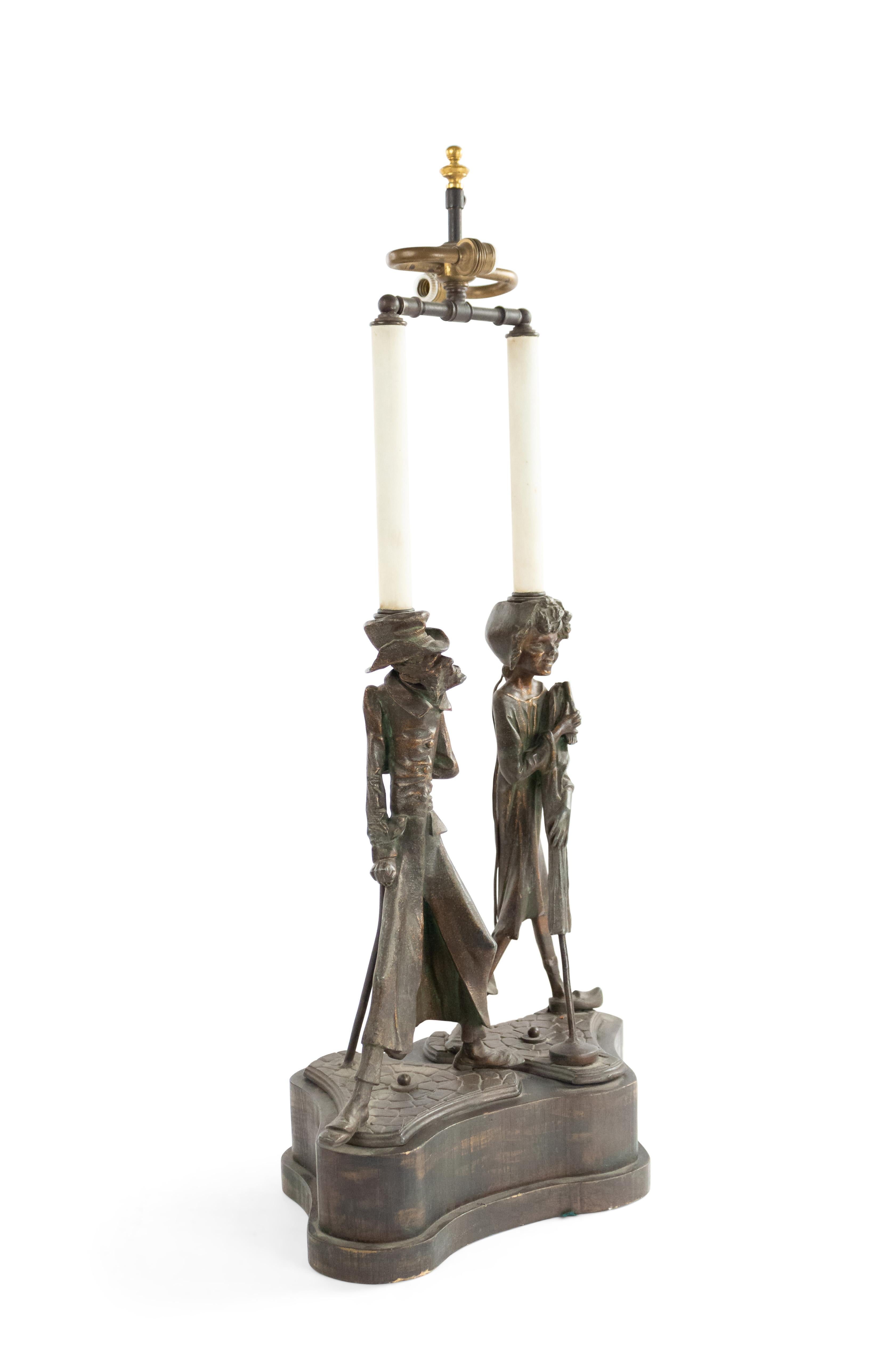English Victorian metal table lamp with character man and woman standing on shaped wood base.
