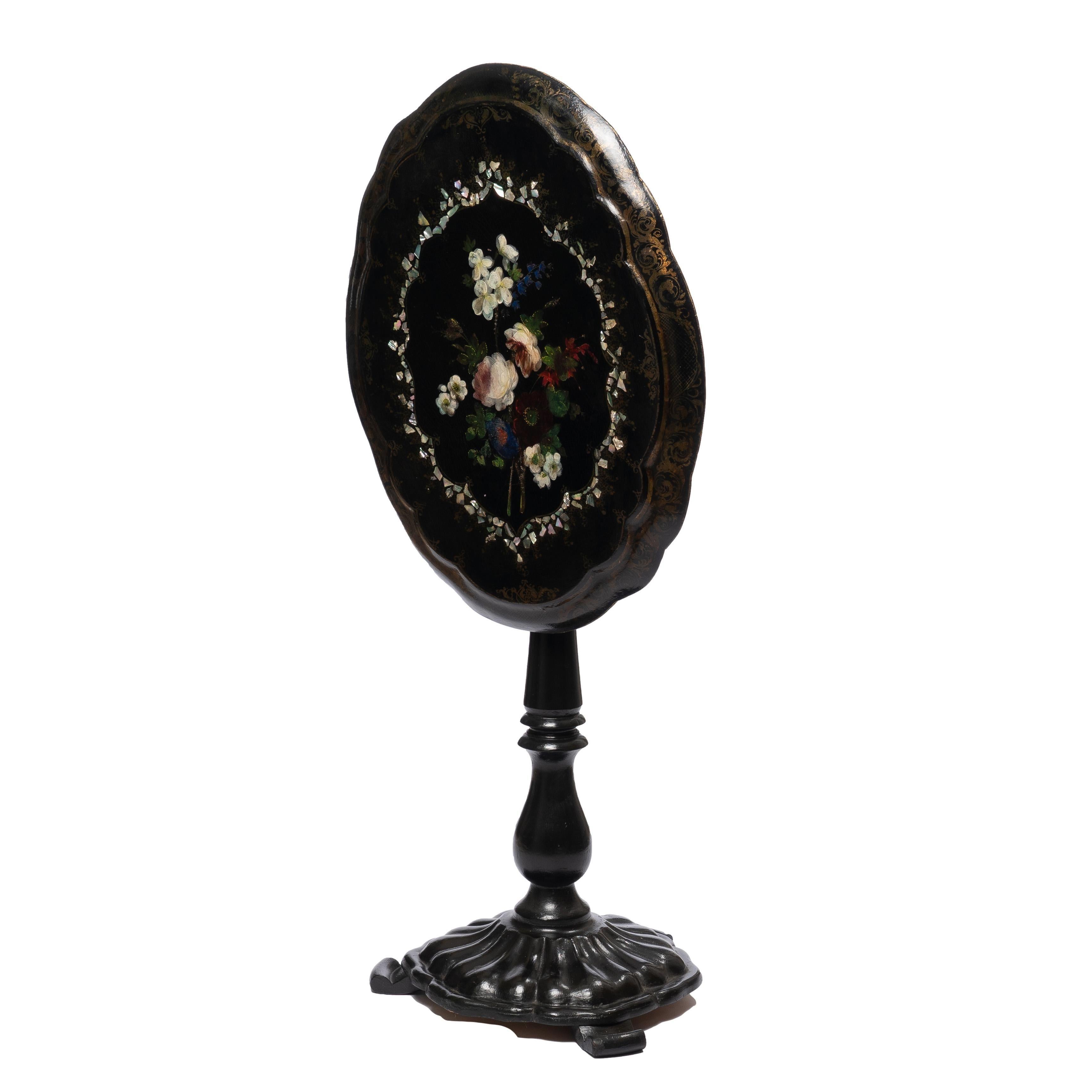 Mother-of-Pearl inlaid and floral painted quatrefoil form paper mache tilt top table. The top rests on a painted wood pedestal with molded base and on three scroll cut feet. The base has been weighted for stability.

England, circa 1860.