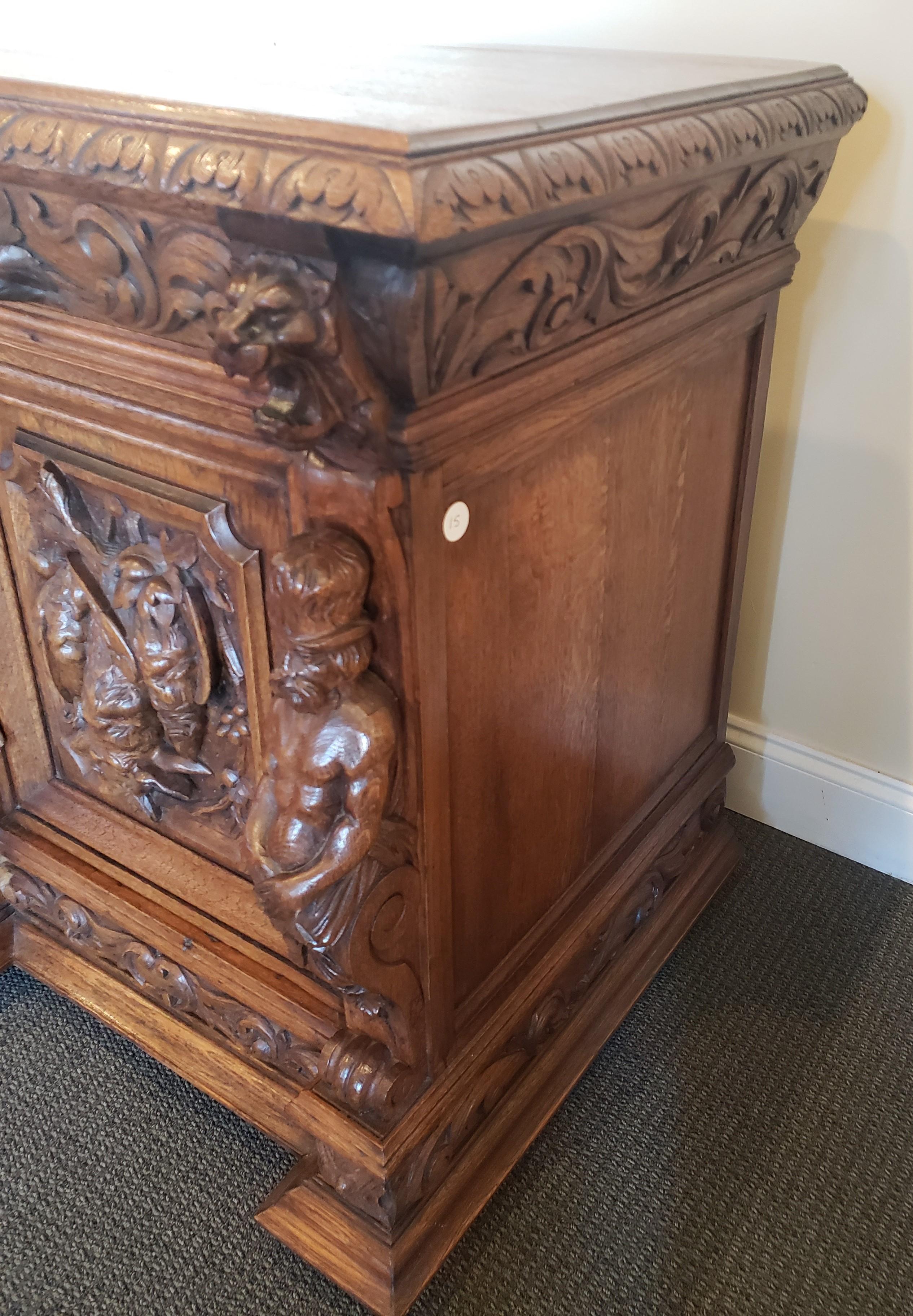 English Victorian oak Jacobean style credenza. This stunning, late 19th century credenza has a profusion of carvings that include full bodied, standing figures that frame the cabinet doors with high carvings of game birds. The 3 drawer pulls are