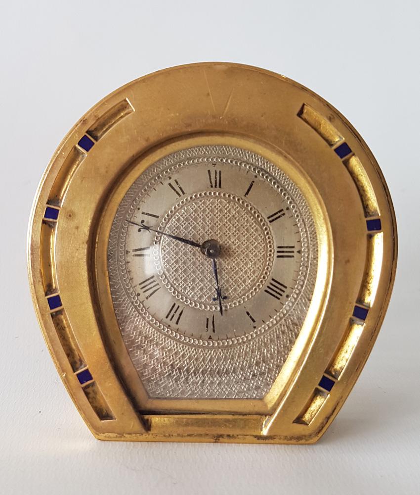 An English ormolu horseshoe clock in the manner of Thomas Cole. Small 3/4 plate movement with dust covers to rear for wind, adjust and regulate. Fine original silvered bronze dial with engine turned decoration. 8 blue enamel 