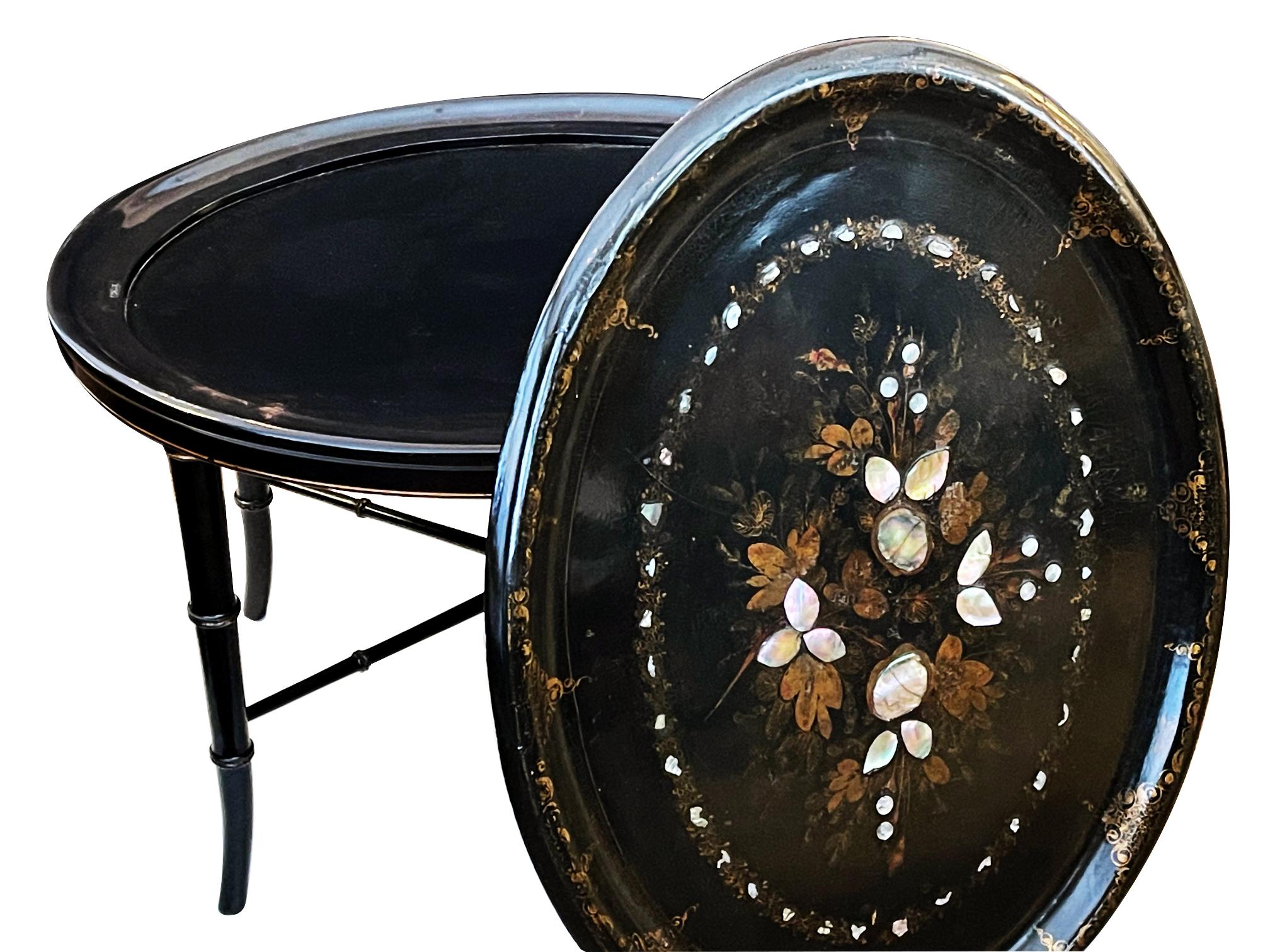 The oval tray with rolled lip centering a painted and inlaid floral bouquet within outer foliate perimeter bands; raised on a later ebonized faux bamboo stand.