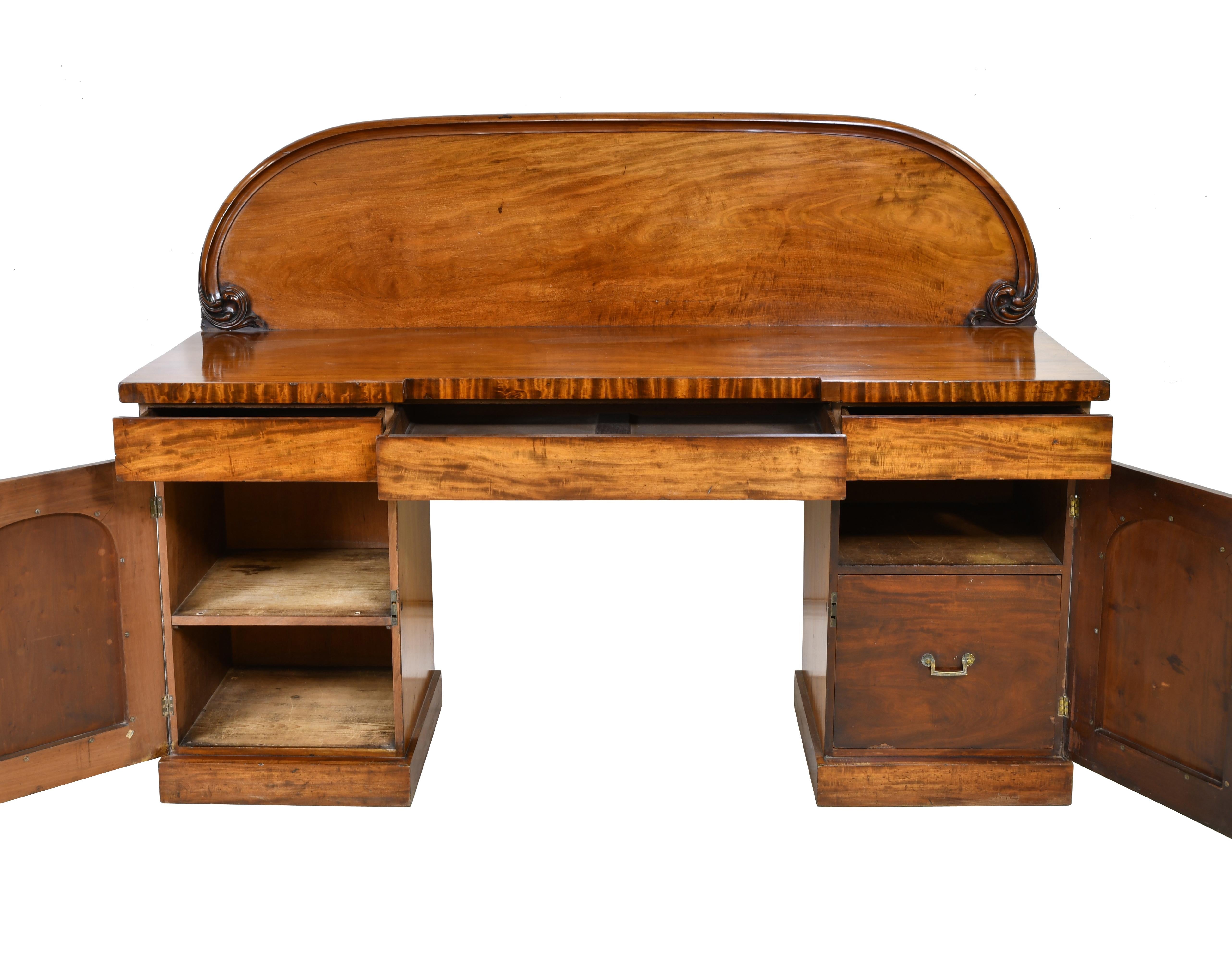 Light figured mahogany pedestal base sideboard with backsplash and ample storage from the mid to late Victorian period in England.
Inside storage includes a shelf in the left cabinet and a large bottle drawer on the right as well as 3 silverware