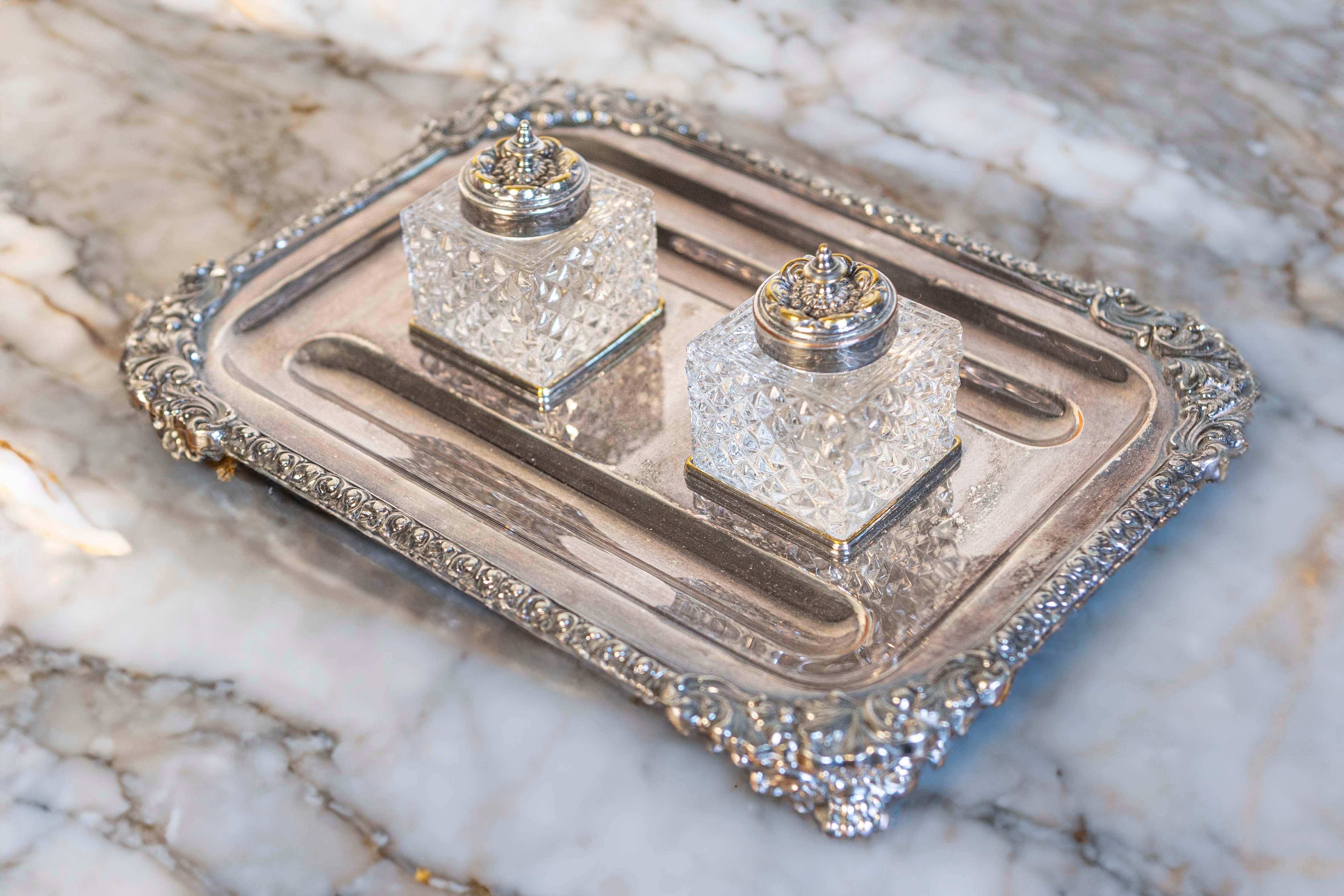 An English stamped silver inkstand from the late 19th century, with two crystal inkwells. Born during the later years of Queen Victoria's reign, this exquisite piece features a silver tray, adorned with delicate motifs on the trim and raised on four