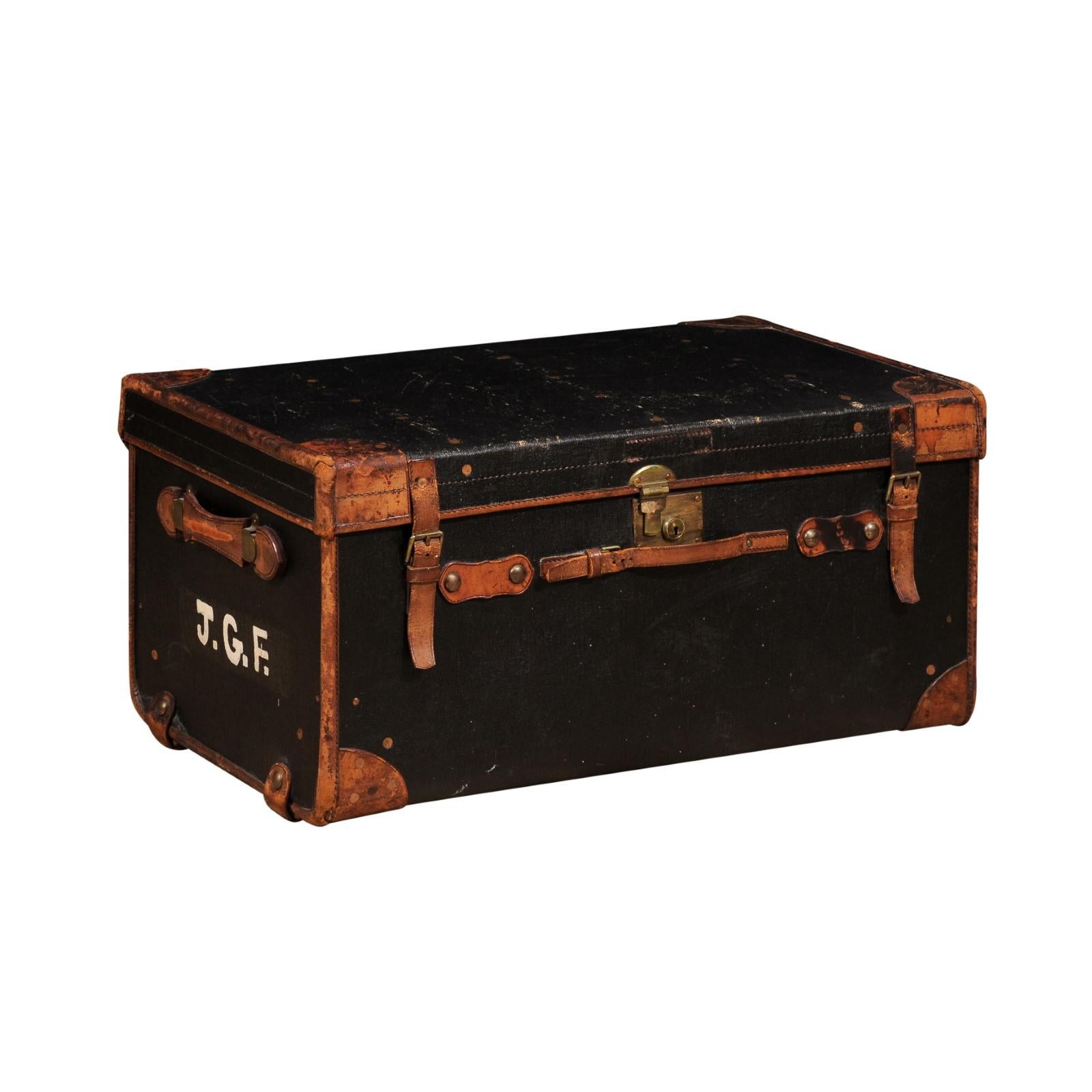 An English Victorian period black and brown traveling trunk from the 19th century with J.G.F initials painted on the side and removable trays on the inside. Presenting a stunning English Victorian period traveling trunk, dating back to the 19th