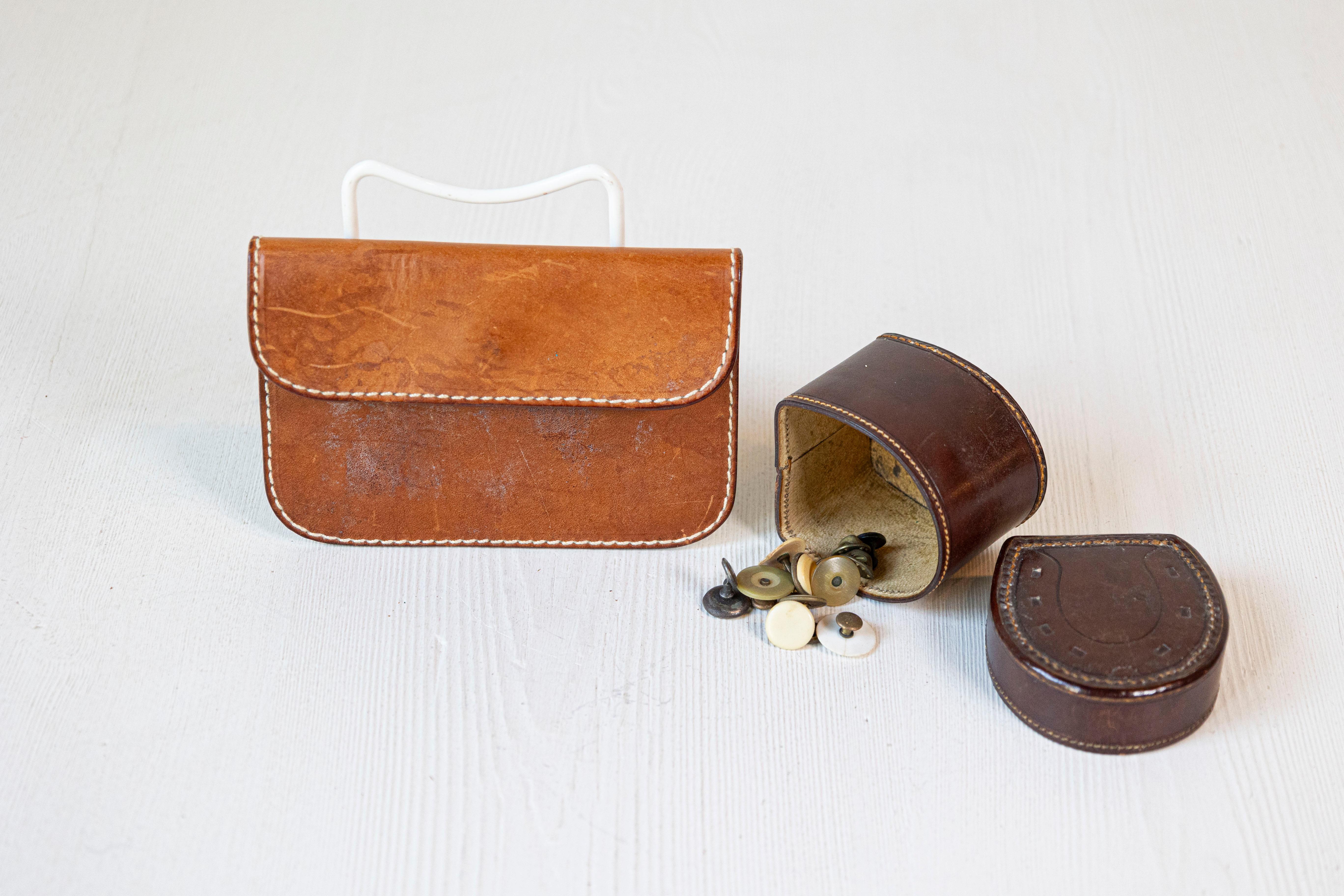 An antique English Victorian period leather case and horseshoe button box from the 19th century, with eleven buttons. Created in England during the reign of Queen Victoria, this leather set features a light brown pouch with stitched trim, opening