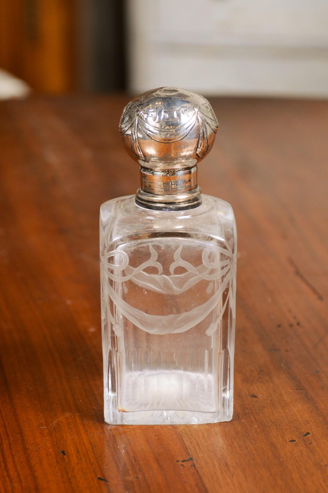 An English Victorian period glass vanity bottle from the 19th century, with silver lid and etched décor. Created in England during the reign of Queen Victoria, this small vanity bottle features a square-shaped glass body adorned with etched