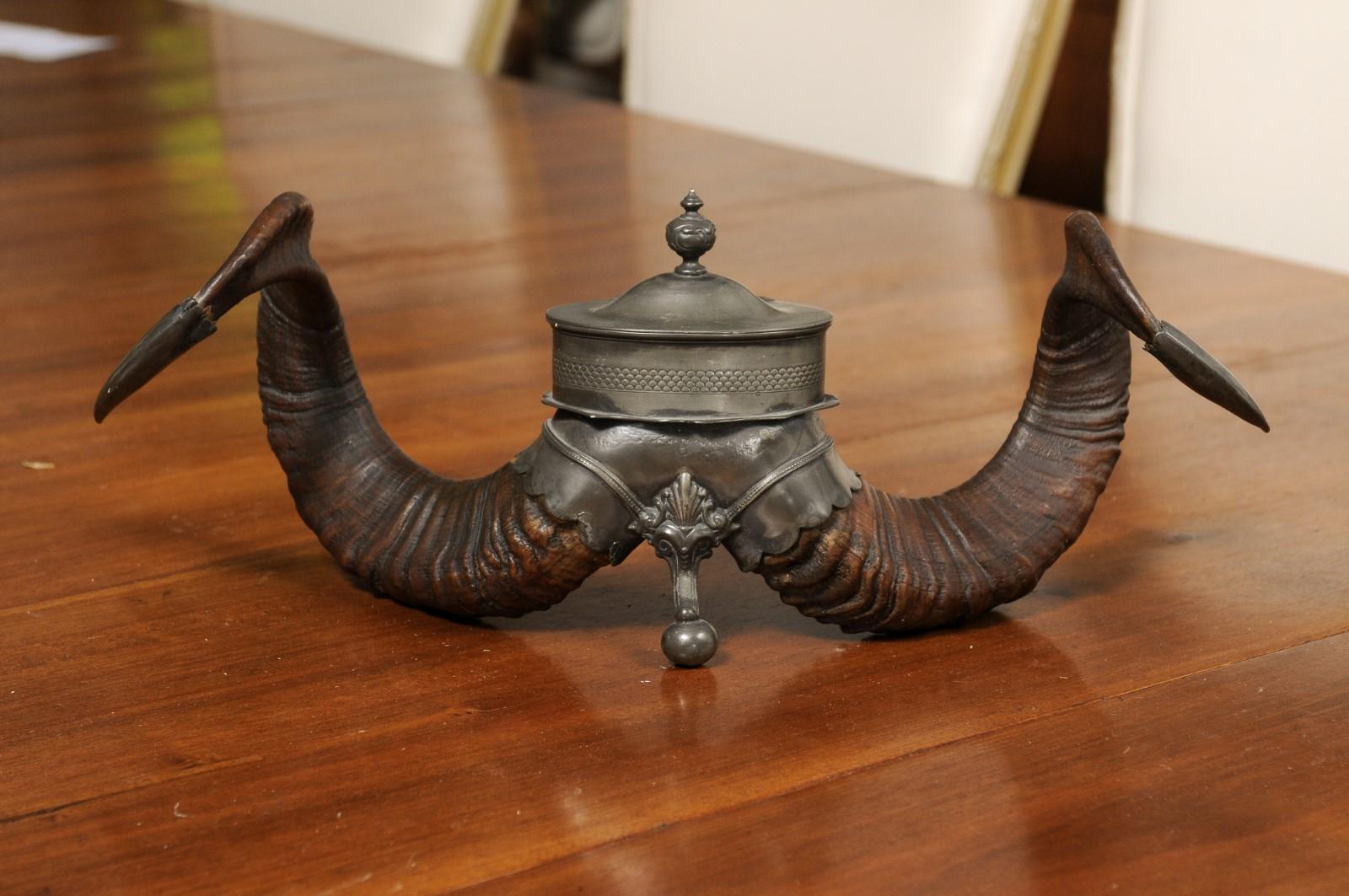 An English Victorian period ram's horns inkwell from the 19th century, with metal canister. Created in England during the reign of Queen Victoria, this inkwell immediately draws our attention with its twisted ram's horns supporting a metal canister,