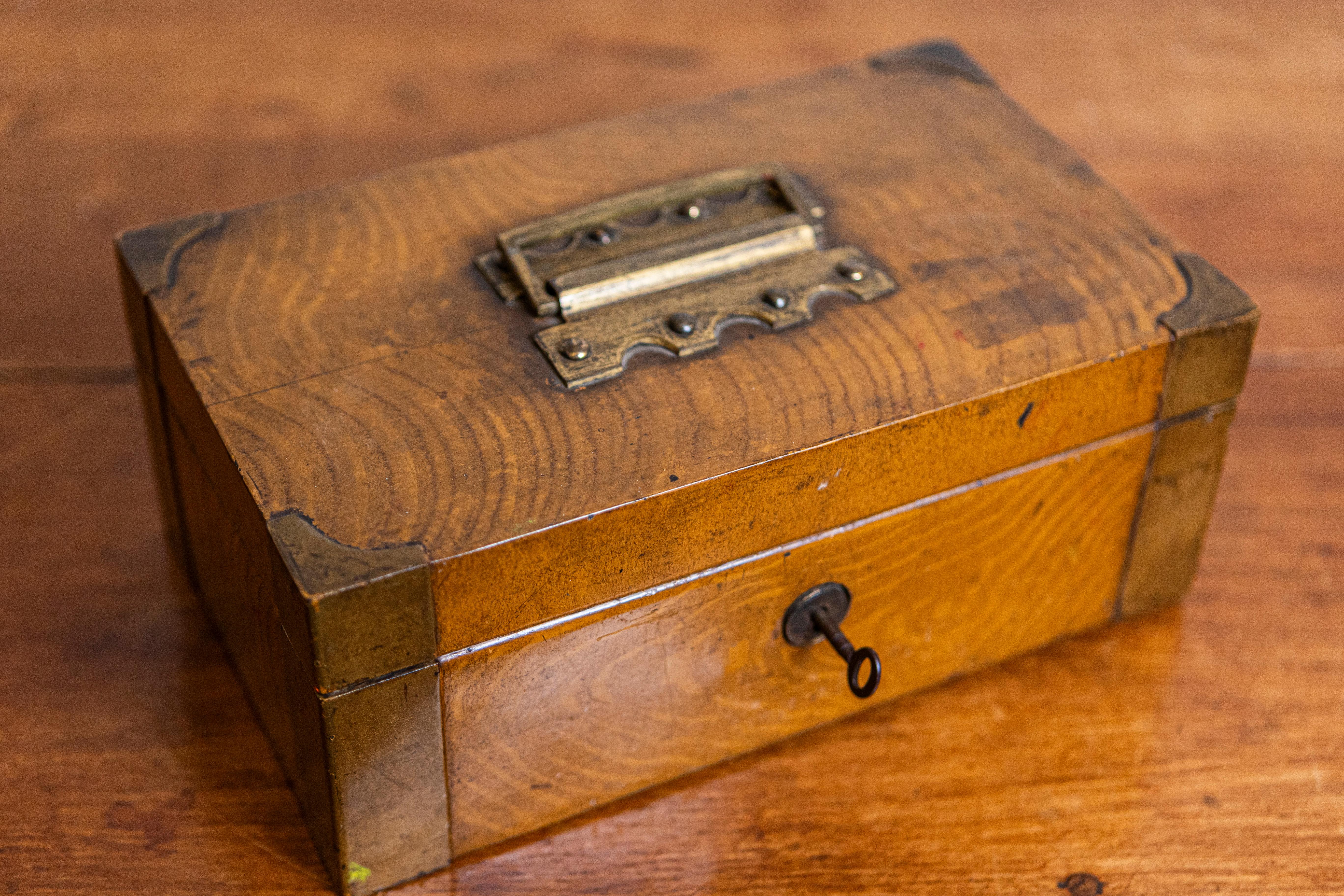 An English Victorian period bank storage box from the 19th century with brass corners and removable metal  interior. This English Victorian period bank storage box from the 19th century exemplifies traditional utility and historical charm. Crafted