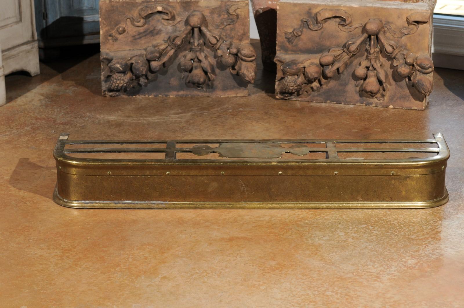 An English Victorian period brass fireplace fender from the late 19th century. Born under the reign of Queen Victoria in the later decades of the 19th century, this brass hearth fender was created to prevent logs from rolling out on the floor.