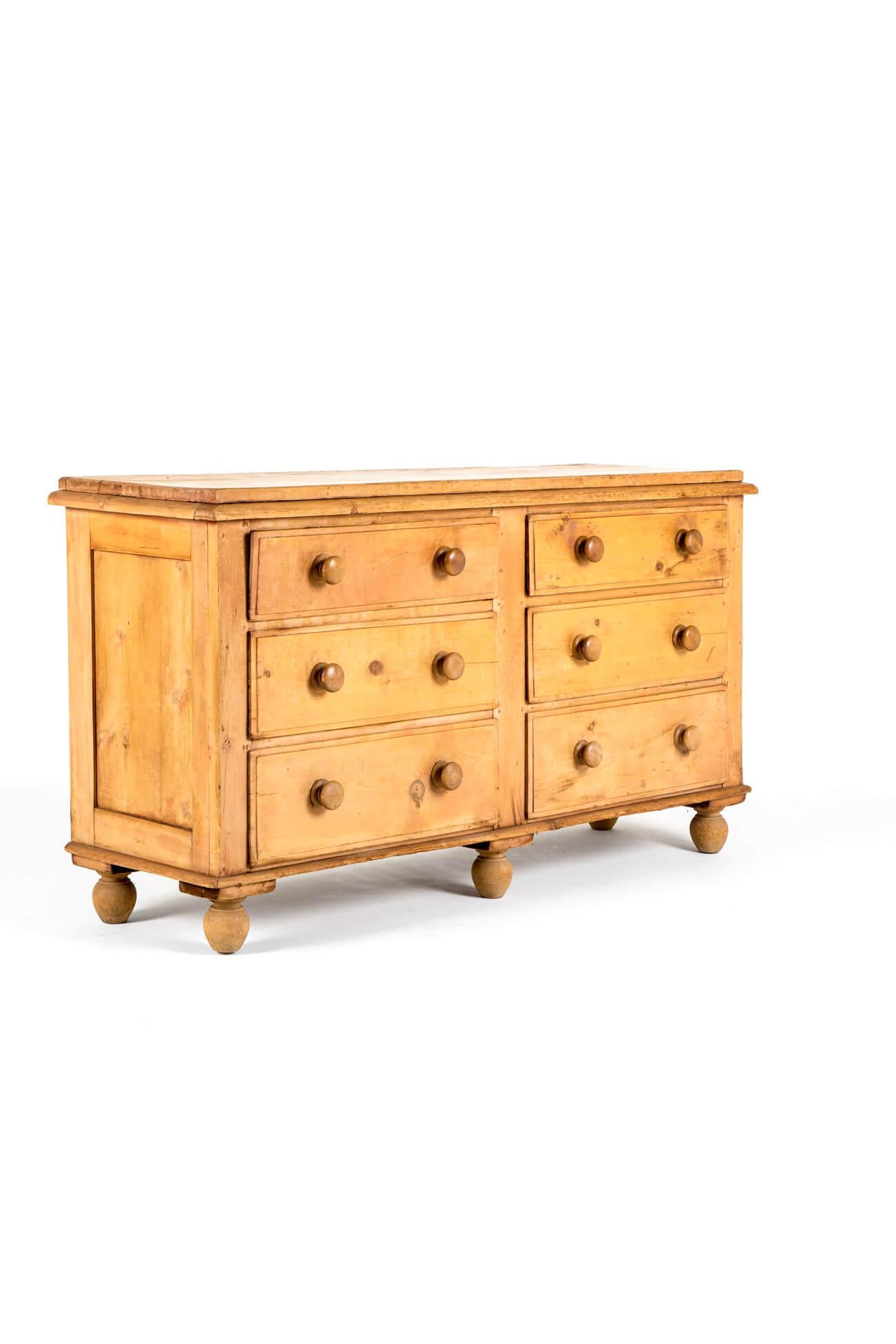 A wonderful country house pine dresser base with a thick moulded plank top with a configuration of six  deep and wide smooth running drawers each fitted with button handles.

La cassettiera è sollevata da sei piedini torniti con uno schienale