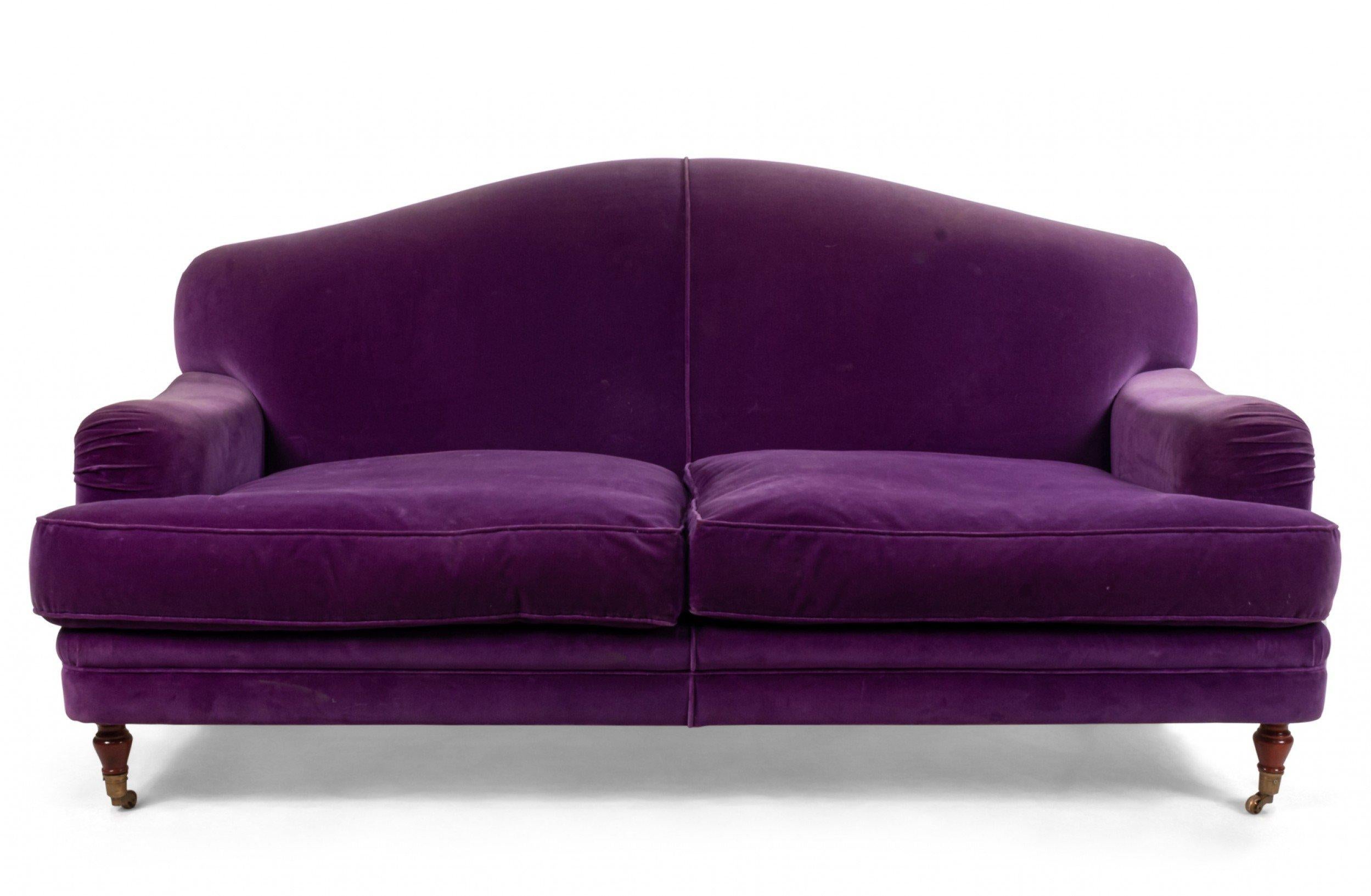 English Victorian style (modern) purple velvet loveseat with turned mahogany legs and 2 seat cushion, 2 red pillows, and 1 blue pillow.
     