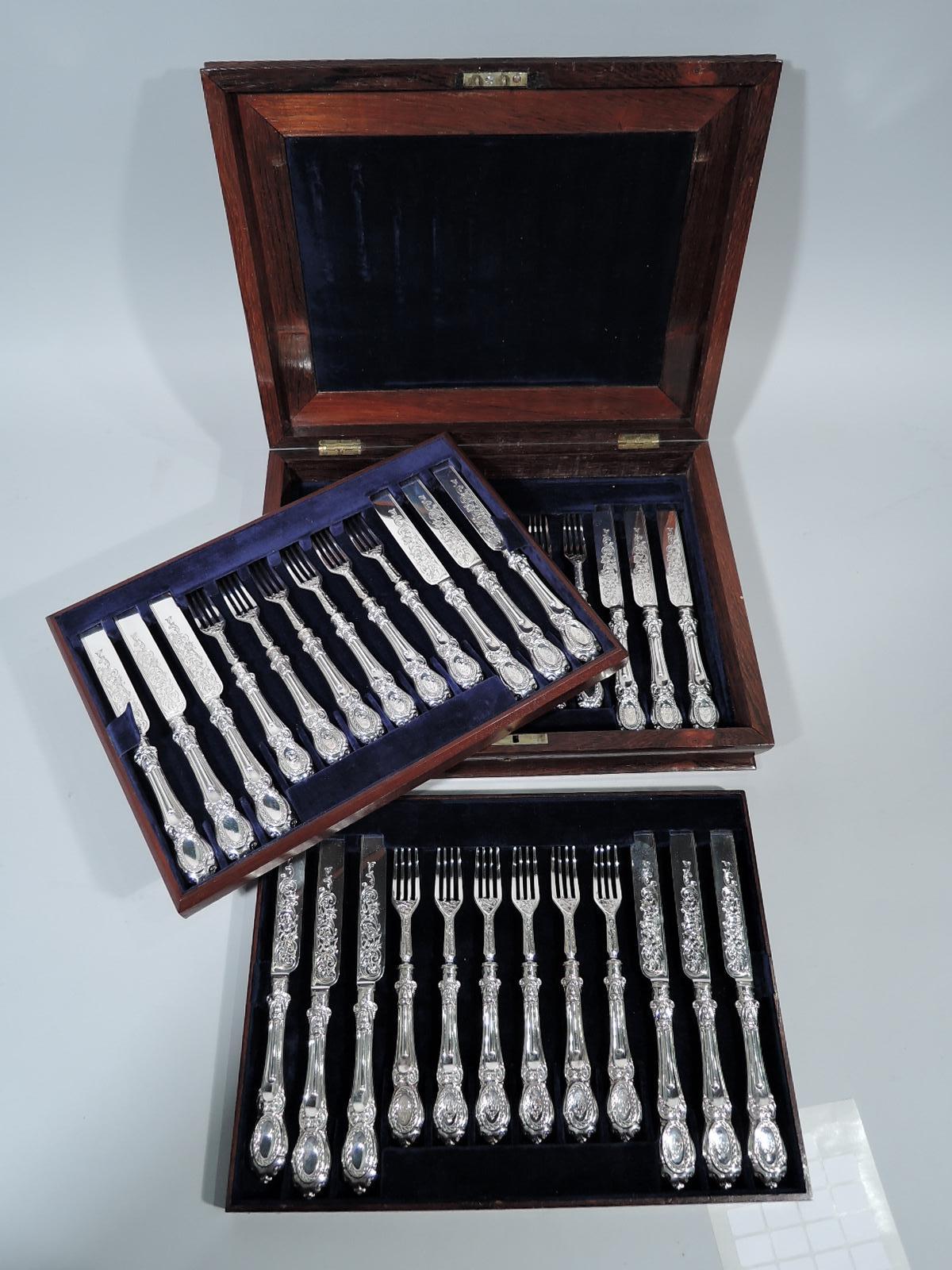 Victorian Rococo sterling silver dessert set. Made by Martin, Hall & Co., Ltd in Sheffield in 1859. This set comprises 18 knives and 18 forks. Textural handle with strapwork cartouche; terminal scrolled with engraved armorial in cabled oval. Blades