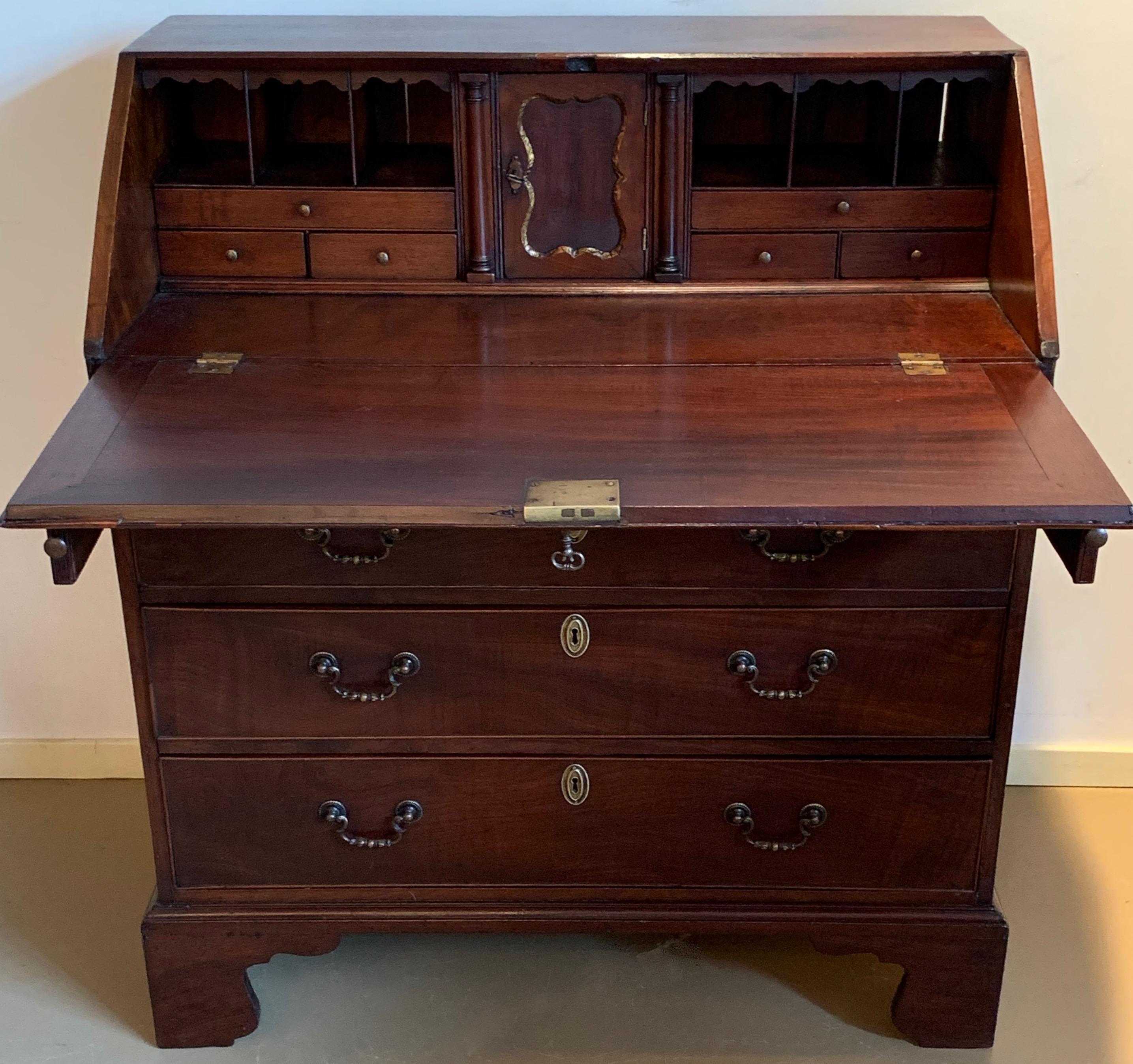 English massive mahogany secretary desk in good condition. This 1860s English secretary desk is made of mahogany with a beautiful patina. Two arms extend from the front of the desk to support the fold down work area. Inside the desk cabinet there