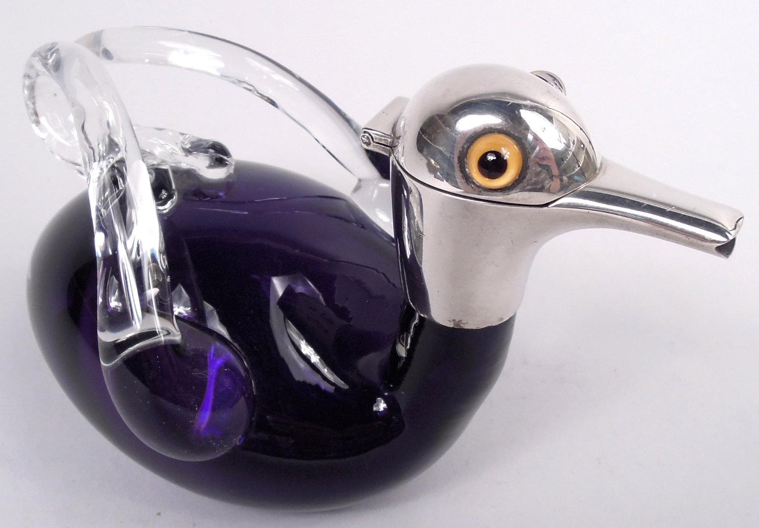 Licorera victoriana. Fabricada por Cornelius Saunders & Frank Shepherd en Birmingham en 1895. Cuerpo ovoide de vidrio morado con alas tubulares transparentes remetidas que forman el asa. Cuello cilíndrico con collar de plata de ley y cabeza