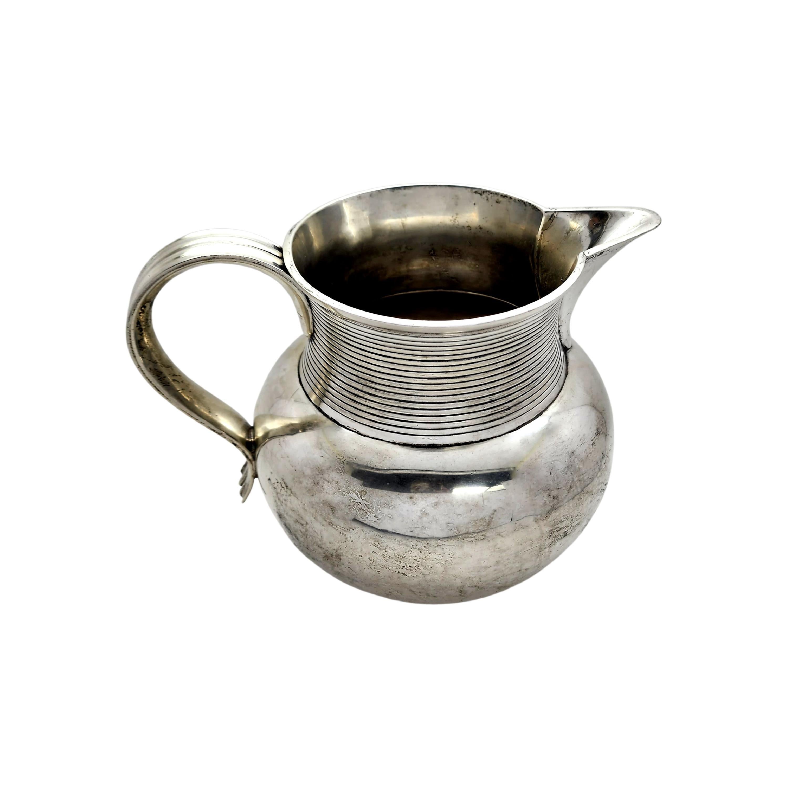 Antique Victorian era sterling silver water jug pitcher by Holland, Aldwinkle & Slater of London, England, circa 1894.

Beautiful and elegant short and wide water jug pitcher, lightly hammered with ribbed design at top.

Measures approx 7