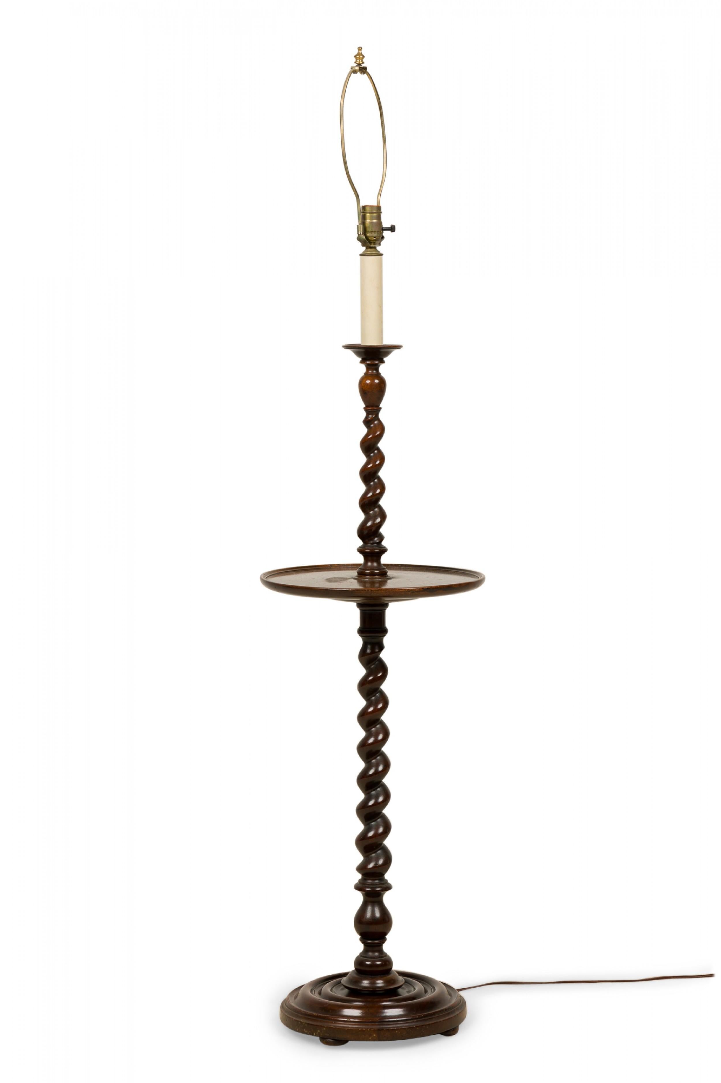 English Victorian-style floor lamp / table with a mahogany turned spindle post with circular table surface in the center of the post, resting on a circular stepped turned wooden base and mounted with brass hardware, topped with a bright green and