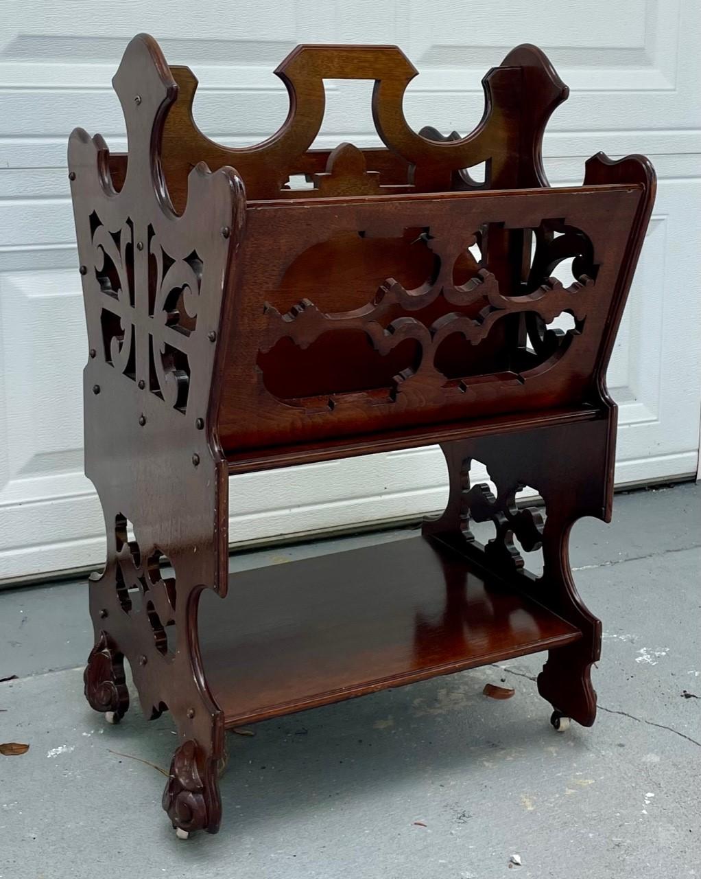 English Victorian Two Tier Walnut Canterbury circa 1880.

Victorian period 1880 canterbury in solid walnut with hand carved scrollwork. This two tiered rolling magazine rack features ornate, pierced woodwork with fret carved side panels and