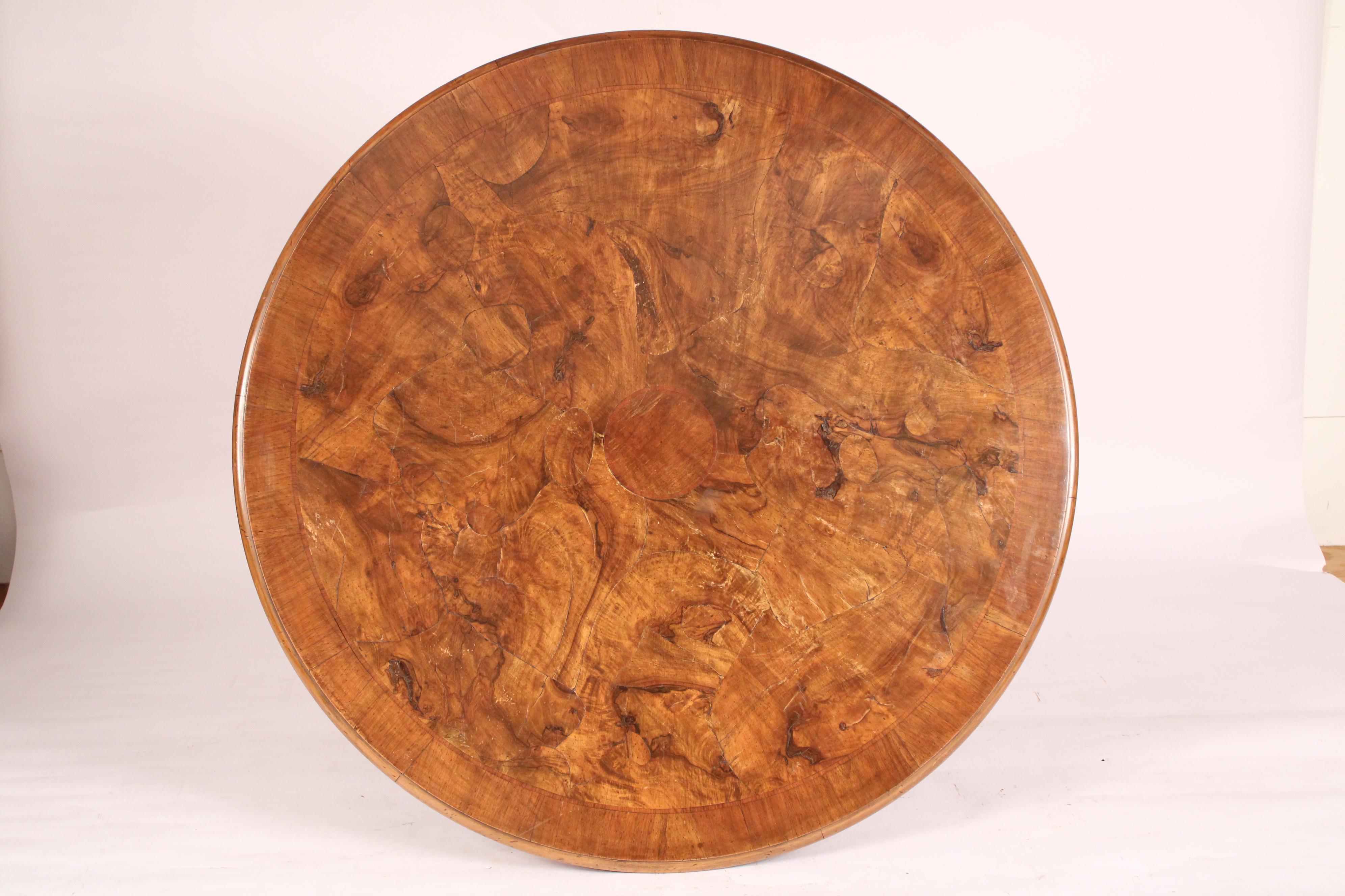 English Victorian burl walnut and walnut center / games table, late 19th century. With a patch work burl walnut round top, a scalloped apron, a central turned and carved pedestal with 4 carved down swept legs ending in snail feet.