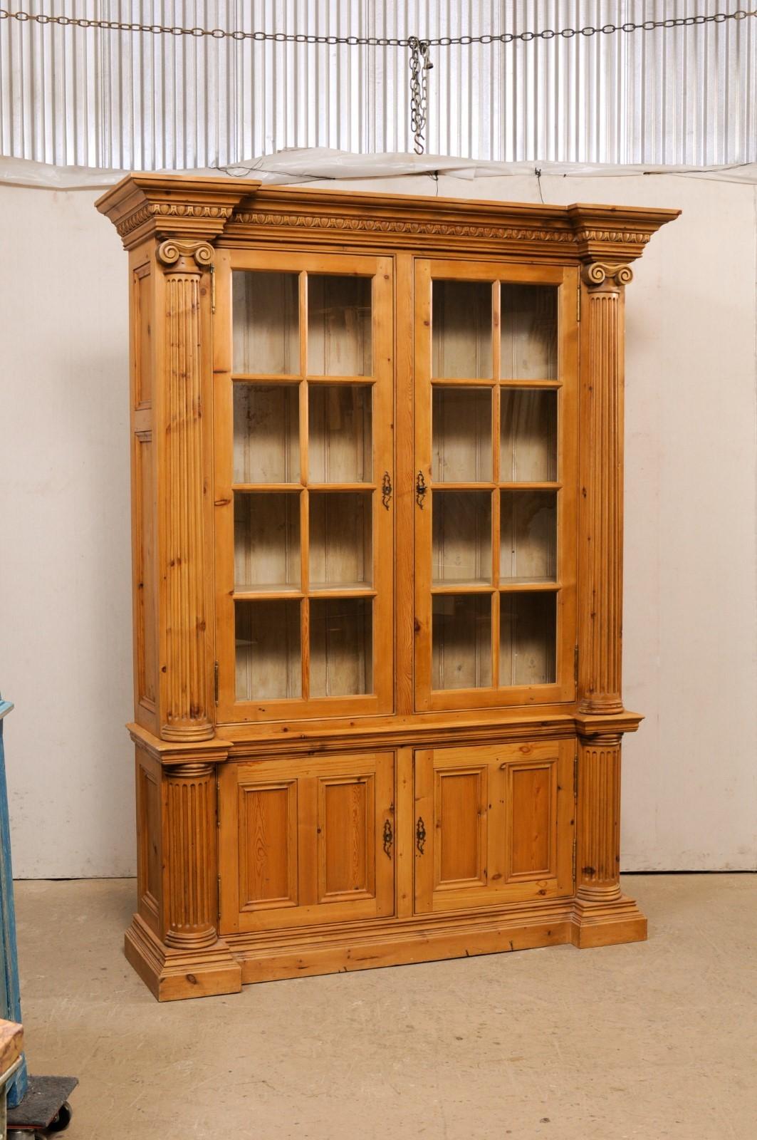 An English nicely-carved and tall wooden display and closed storage cabinet. This vintage cabinet from England is nicely sized, standing approximately 8 feet in height and just shy of 6 feet in length. It is designed with a subtle reversed