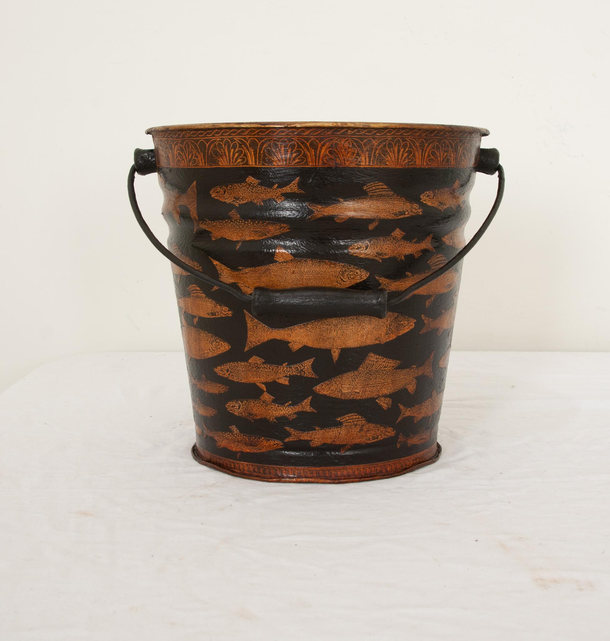 An English vintage metal pail recently painted black and decoupaged with an attractive pattern of fish. Handmade in southern England, this vintage bucket has been recently restored and decoupaged with a pattern of an eye-catching variety of fish and