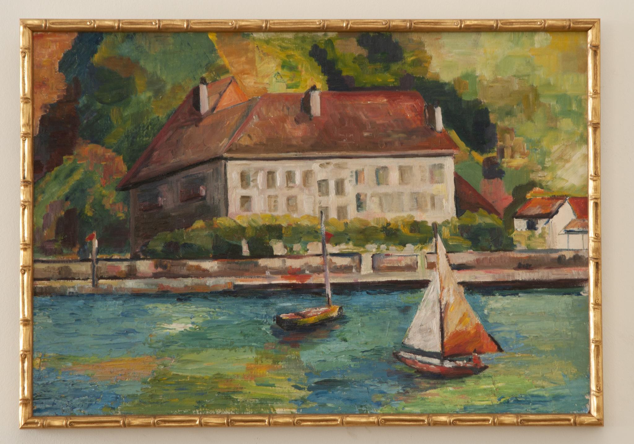 An English 20th century oil painting of a nautical scene recently framed in attractive gilded faux bamboo. This artwork depicts a lush riverside setting with boats on the water in front of a large European house or hotel. Rendered in the