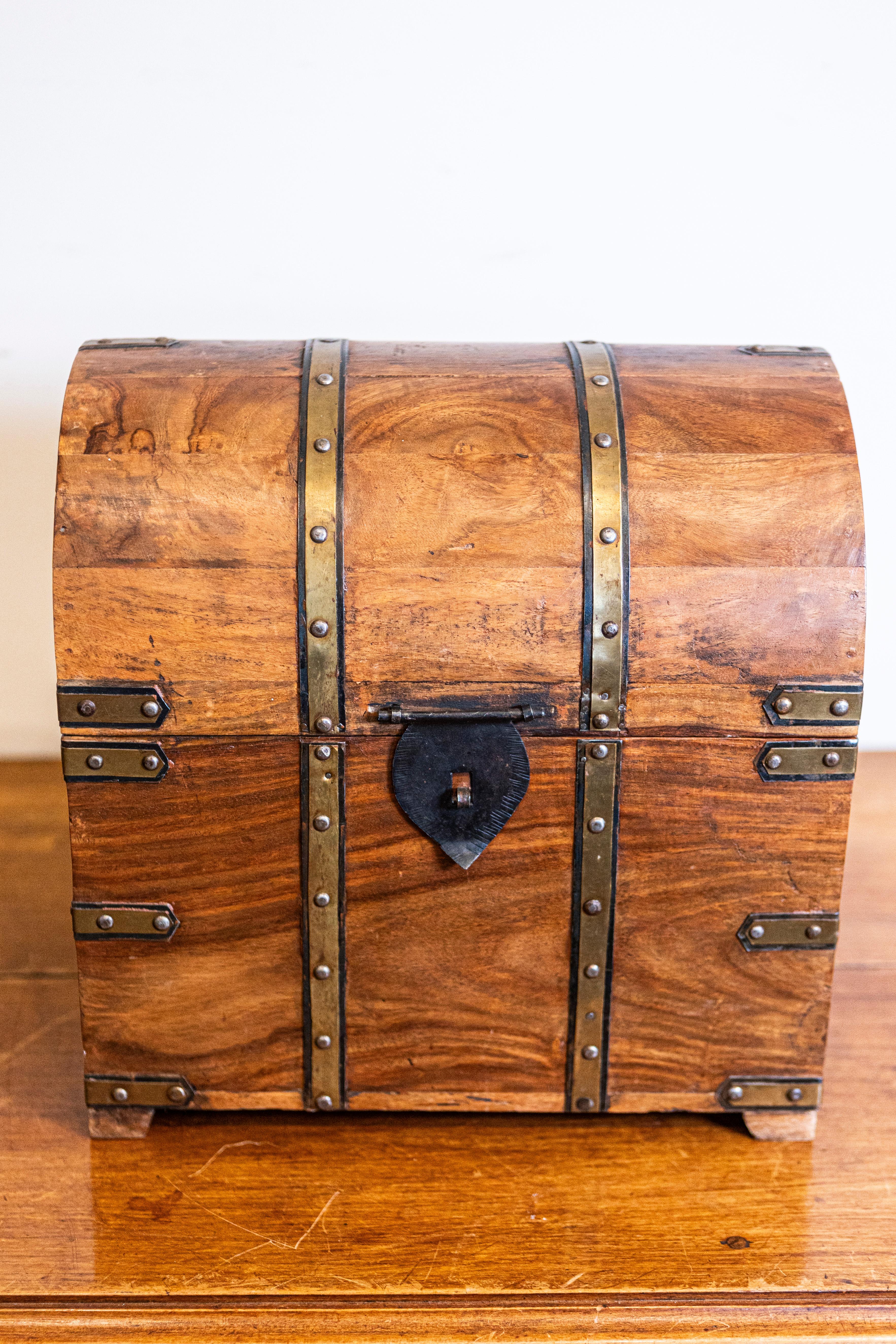 An English vintage wooden treasure chest-shaped cellarette from the 20th century with dome top and brass braces. This English vintage treasure chest-shaped cellarette, crafted in the 20th century, captures the allure of classic design with its