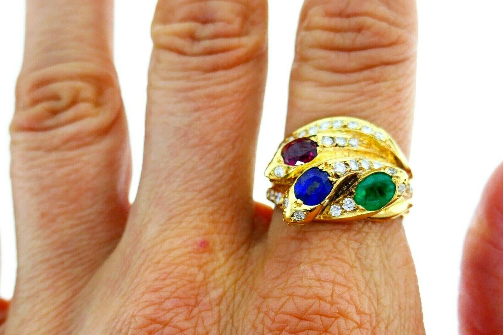 Vintage 18k yellow gold diamond ring with three snakes motif. Featuring oval cut ruby, emerald and sapphire.  Approximate carat weight for diamonds is 1.25 cts. Stamped with a hallmark for 18k gold, English maker's marks and a serial number.