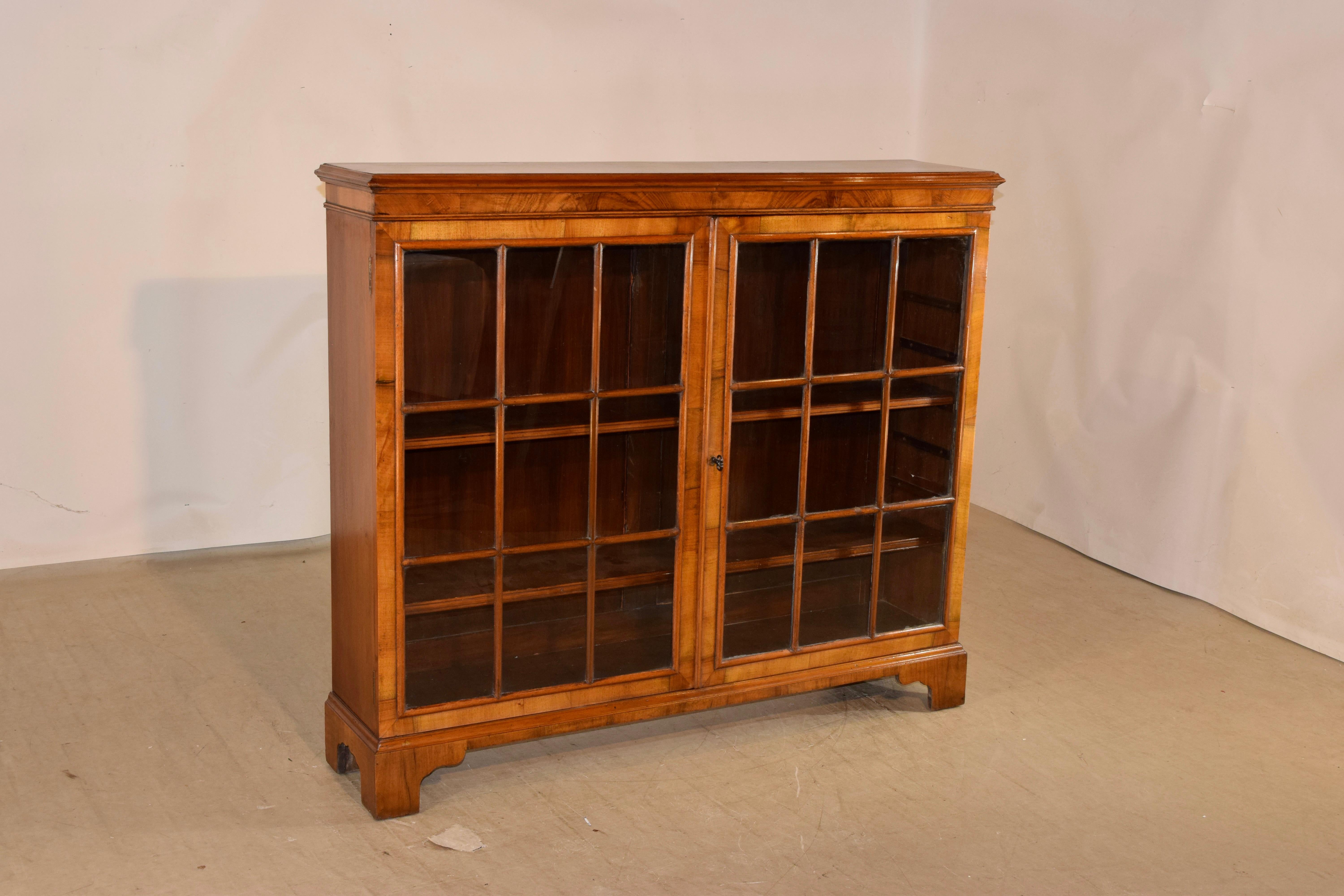 Edwardian walnut bookcase from England, circa 1900. The top has been beautifully book matched and banded with a beveled edge as well, following down to a simple apron with lovely graining patterns over two doors with paneled glass. The sides are