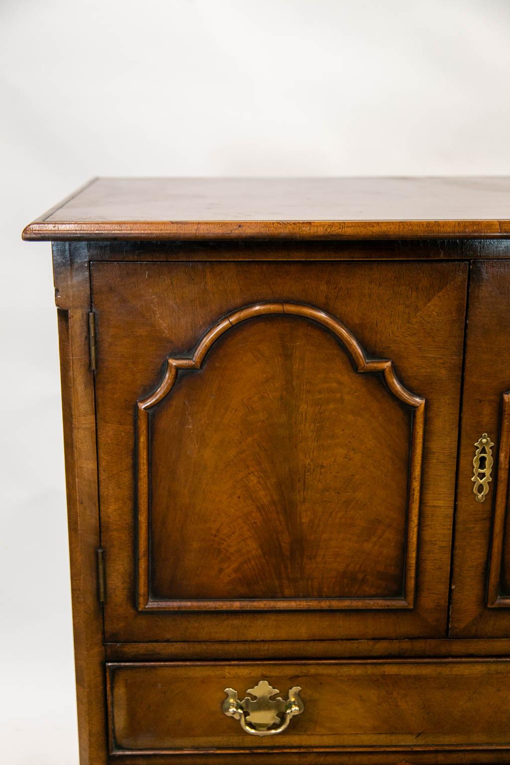 The top of this English walnut cabinet is cross banded with walnut and has burled bookmatched veneer. The base has legs carved with acanthus leaves that terminate in drake feet. The hardware is original.