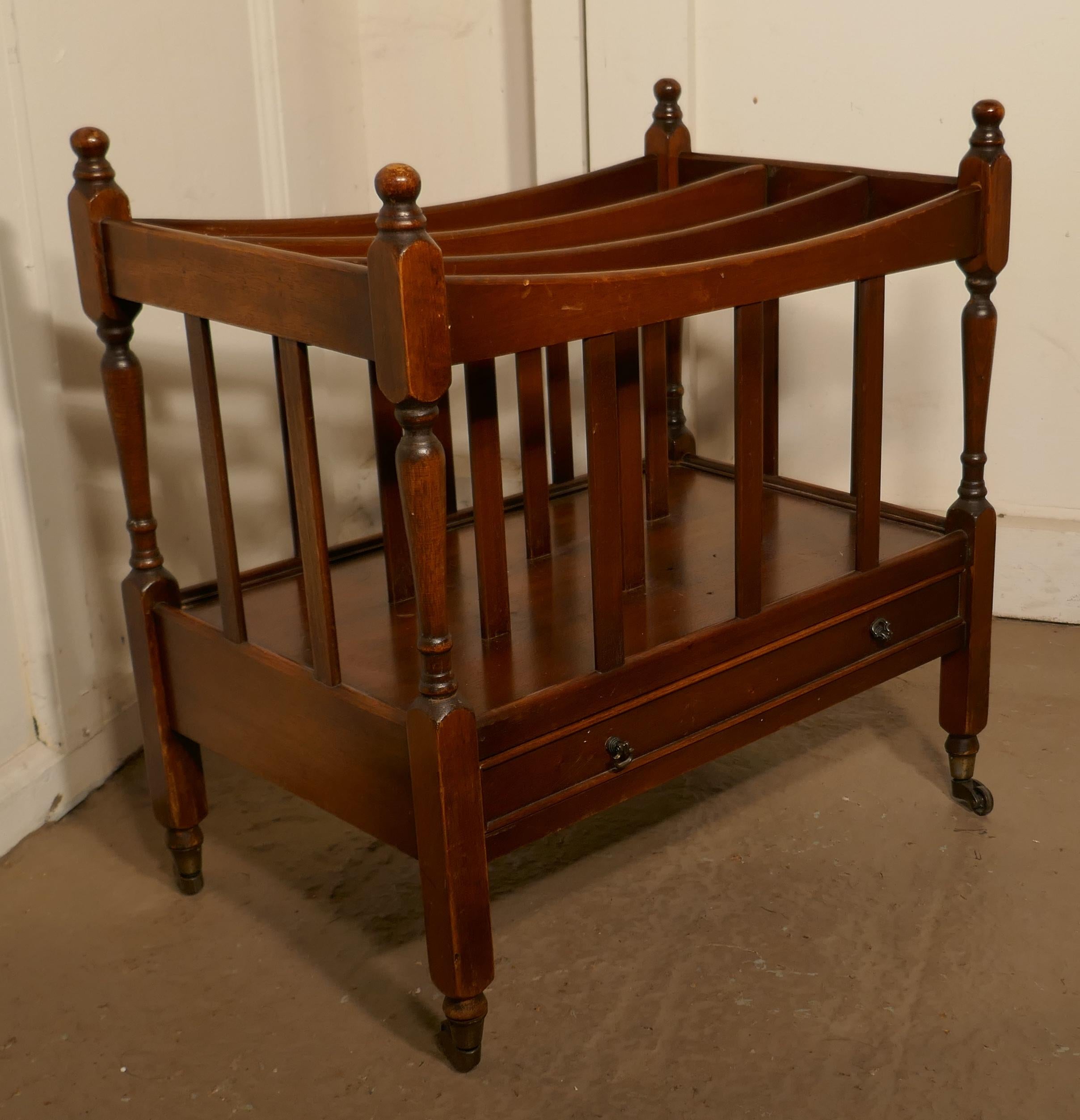 English Walnut Canterbury Magazine Stand

This is a pretty little piece, it stands on neat brass casters and has elegant turned uprights which end in crisply turned finials with 3 compartments and a long drawer at the bottom
An excellent and good