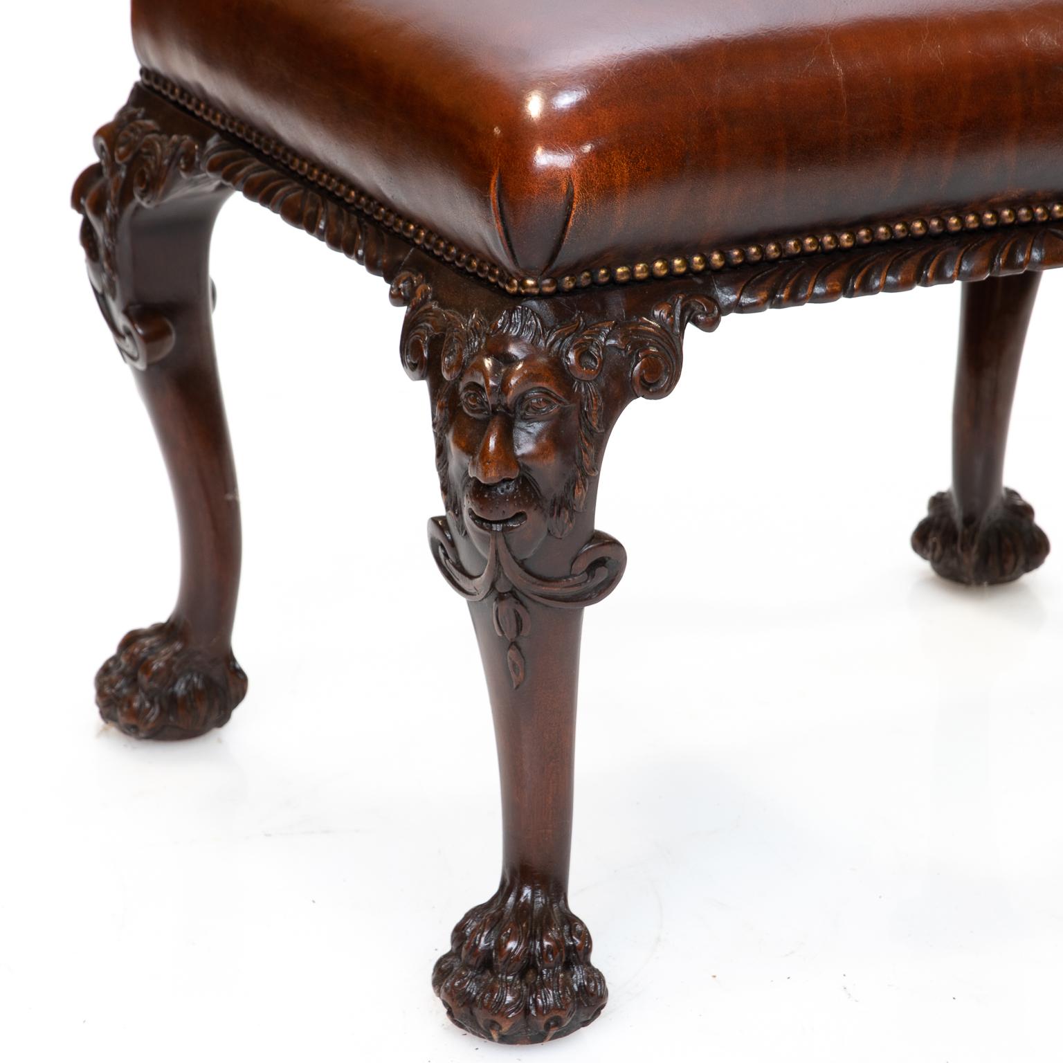 A 19th century walnut Chippendale style, English made, carved stool with leather covering. This stool has been refinished and reupholstered with a leather seat. Carved with face knees, acanthus leaf and claw and ball feet. A fine example of Thomas