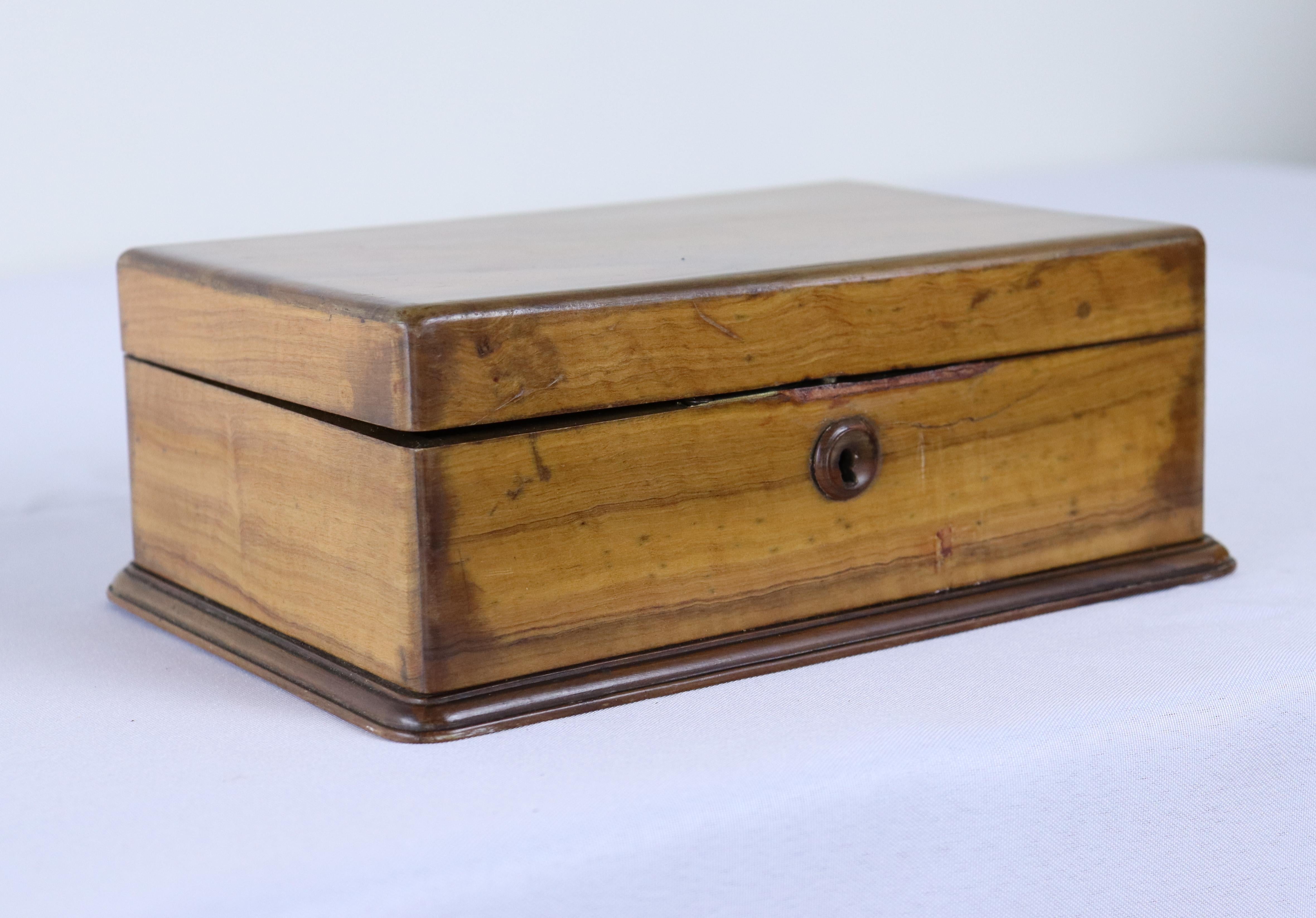 A small walnut box filled with checkers pieces, stained light and dark.  The box has wonderful walnut grain and patina.  There is some wear along the opening of the box, visible in the thumbnail photos.