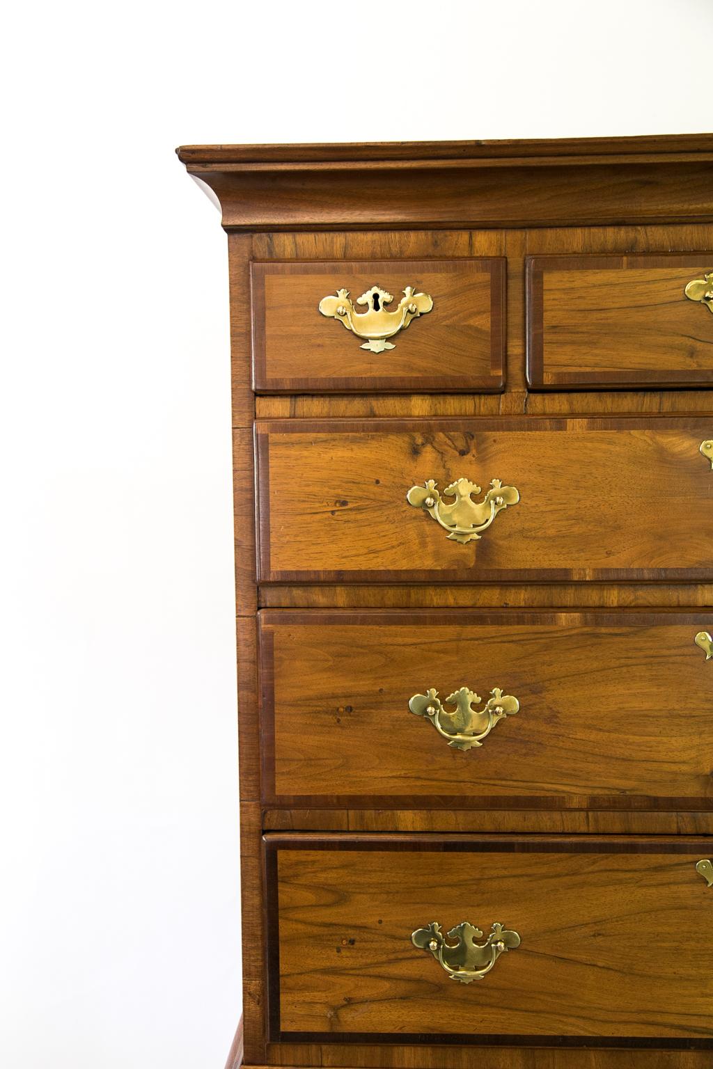 English walnut chest on chest has drawers that have book matched veneers and are cross banded with mahogany. The finish has been restored at a later date, and the hardware is later.
 