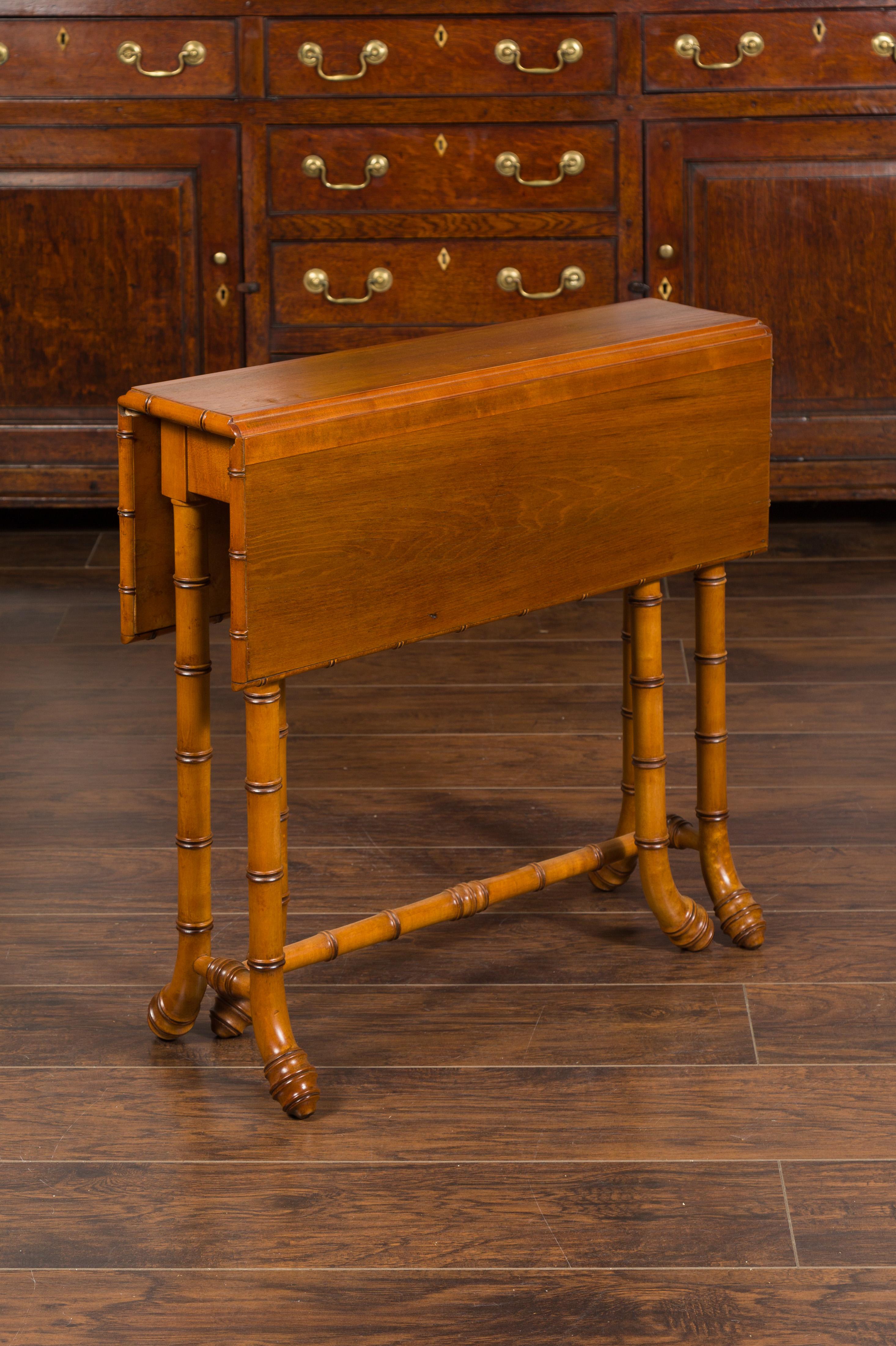 An English walnut drop-leaf table from the early 20th century, with faux-bamboo base. Created in England during the early years of the 20th century, this walnut table features a nearly square top presenting two drop leaves resting on swivel legs