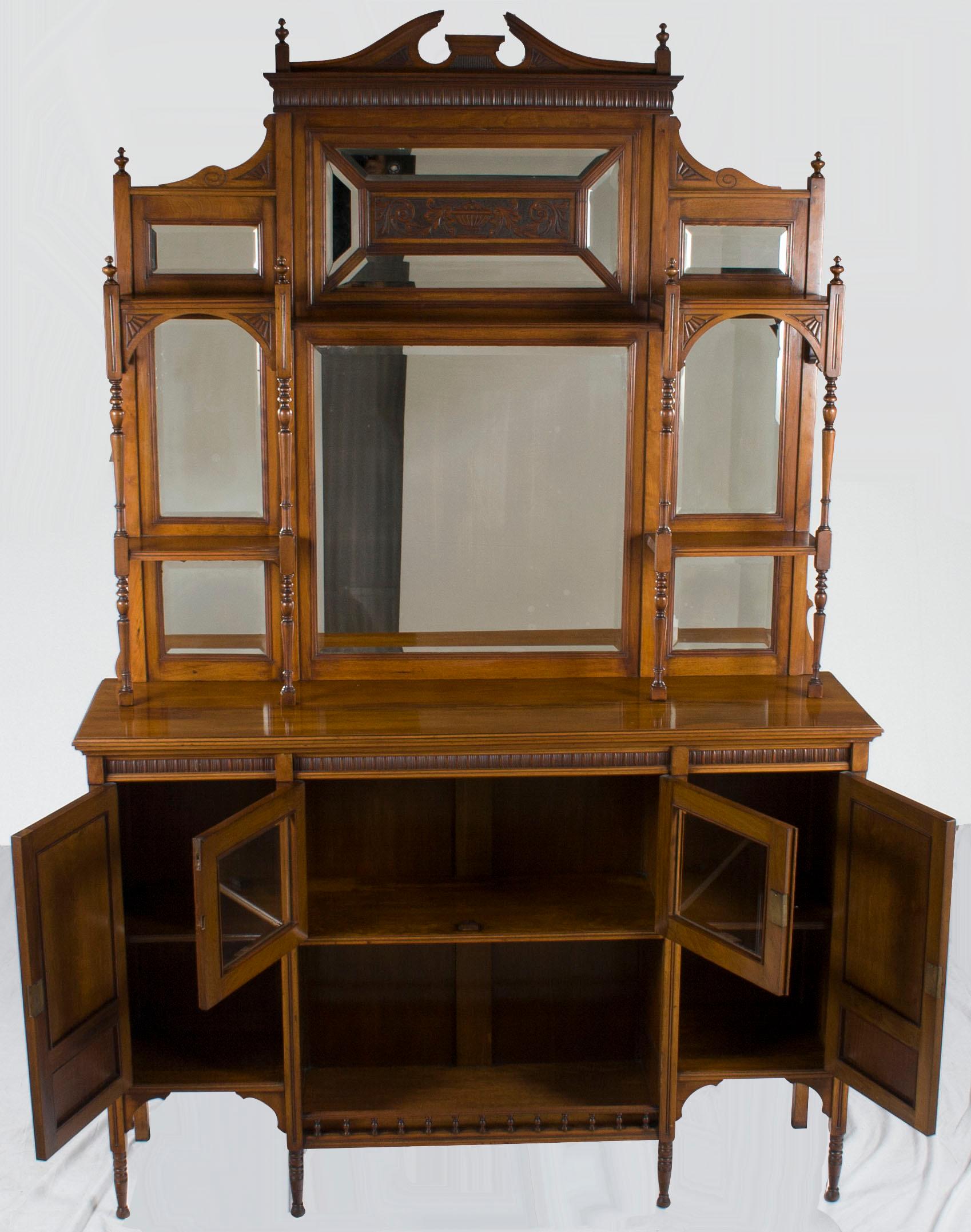 This beautiful English chiffonier was made during the Edwardian period, circa 1910. The walnut boasts a wonderful light brown color, accented with beautiful hand carvings. The large back features several beveled mirrors and small shelves supported