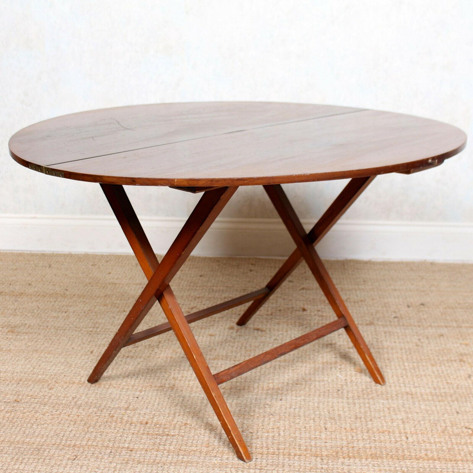 An impressive rare form walnut folding coaching table.

The hinged circular top raised on slender tapering cross-banded legs united by stretchers,

England, circa 1920.