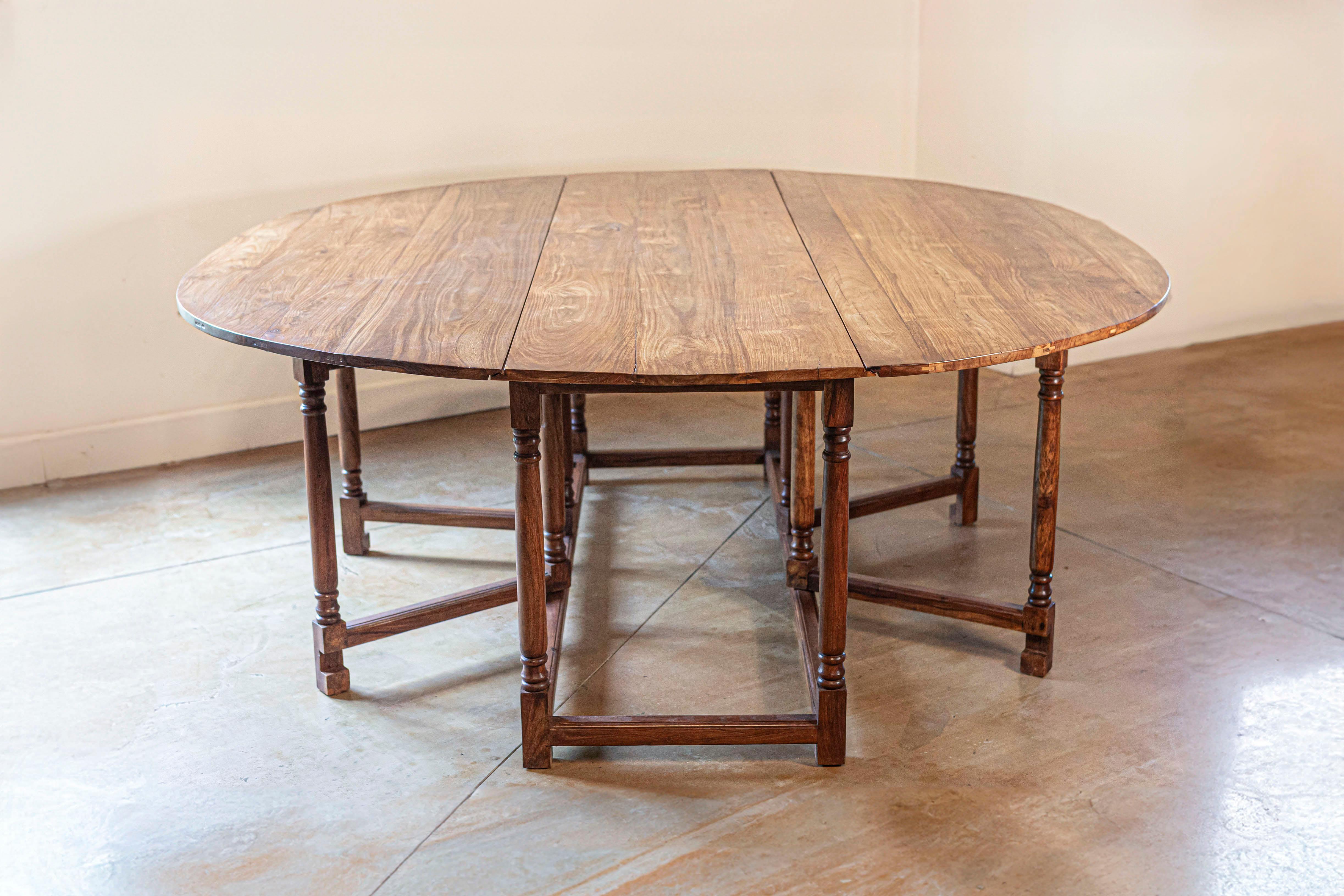 Table en noyer anglais du 20e siècle, à pieds tournés et à brancards simples. Créée en Angleterre au cours du XXe siècle, cette table en noyer à piètement en forme de porte présente un plateau ovale (mesurant 73