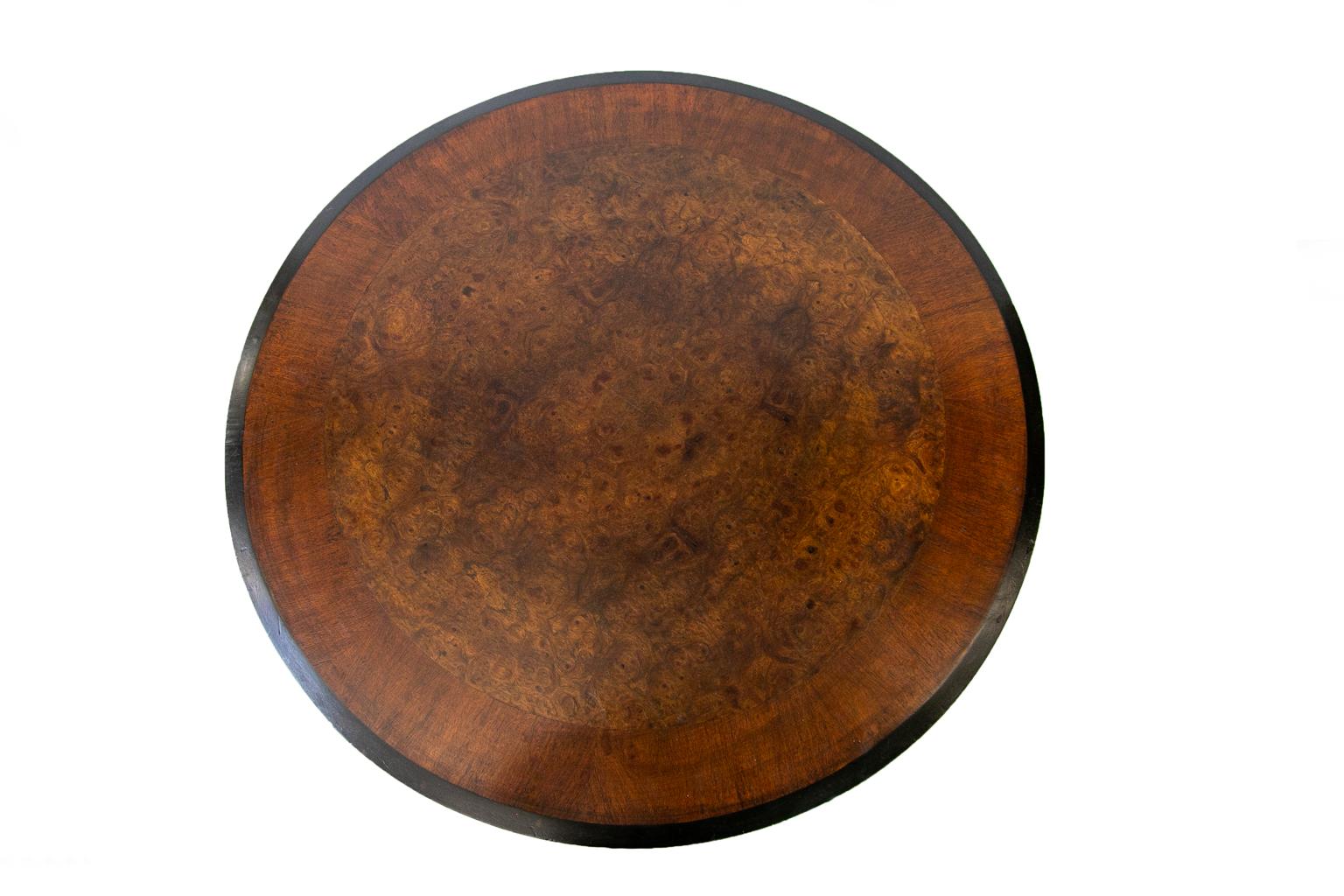 English walnut pedestal center table, the top having bookmatched burl walnut veneer, is crossbanded with a three inch border, and has a beveled black edge. The top edge is also crossbanded throughout the circumference. The support pedestal is