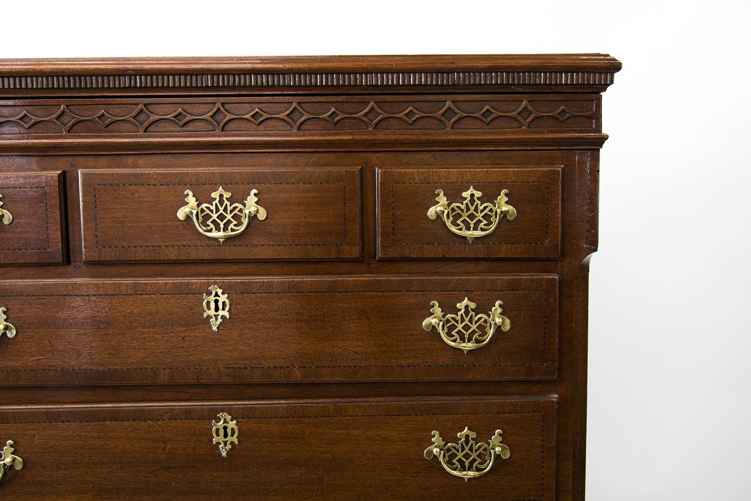 English walnut tall chest, has seven drawers and a crossbanded and ogee molded top with ribbed molding below. The frieze has blind fretwork which disguises a secret drawer which cannot be opened without opening the uppermost long drawer. This long