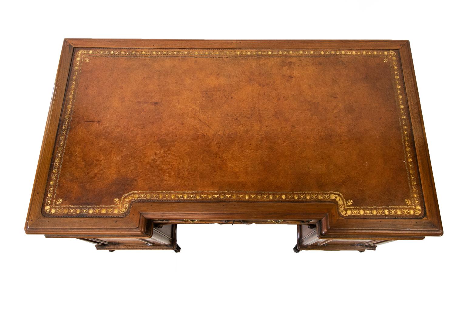 English walnut two pedestal desk has a recessed center and a brown gold tooled leather top.